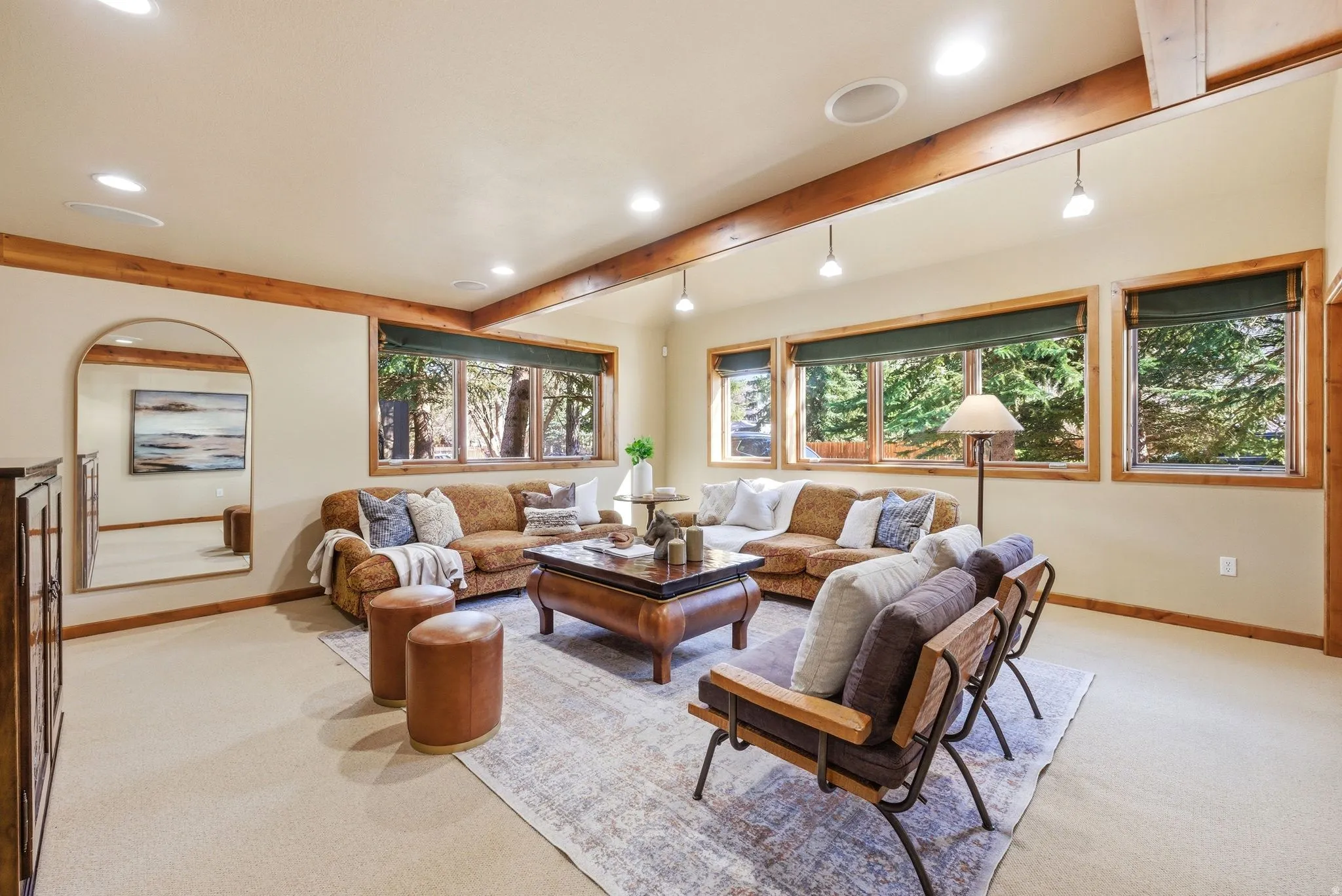 Spacious living area featuring exposed wood beams, recessed lighting, and large picture windows