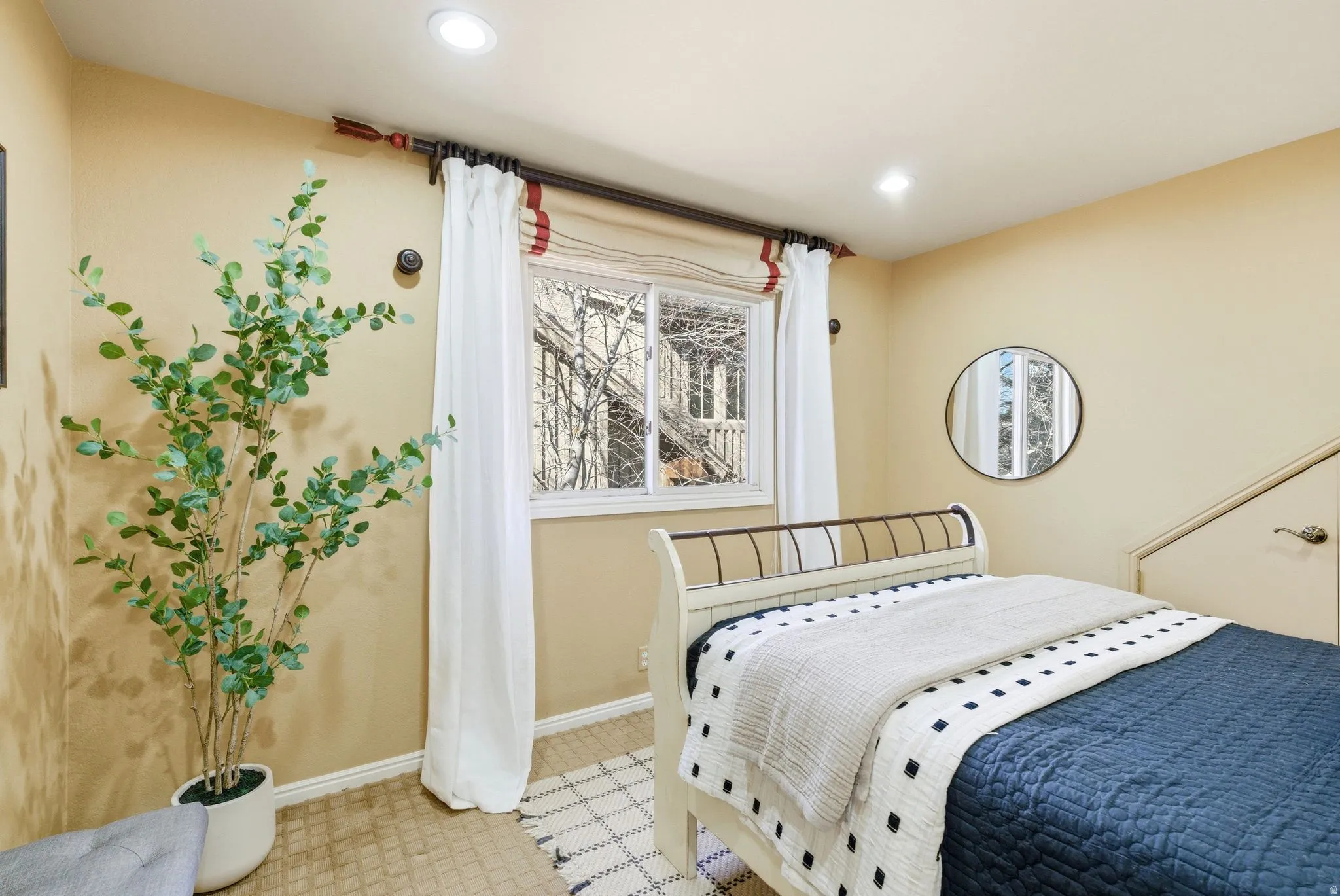 Recessed ceiling lighting illuminates a window with white drapes and a transom rod