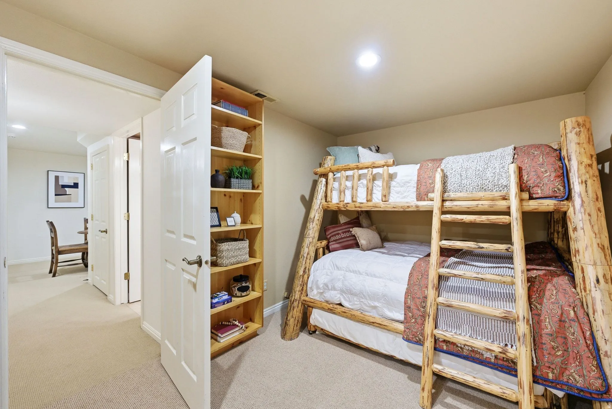 Recessed lighting illuminates a carpeted bedroom featuring a built-in wooden shelving unit