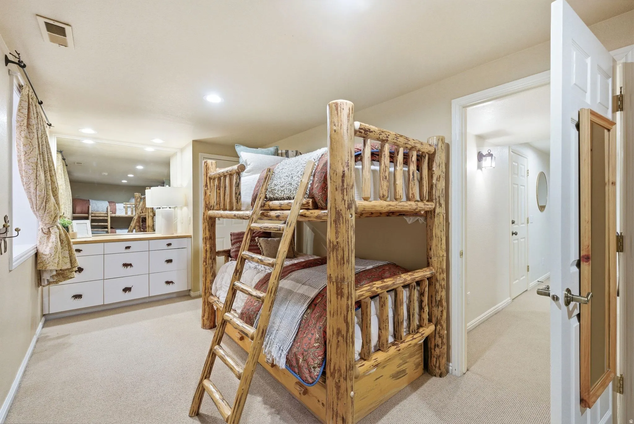 Carpeted room featuring a rustic wood-frame bunk bed, a built-in dresser with white drawers and a wood-finish countertop, and recessed lighting