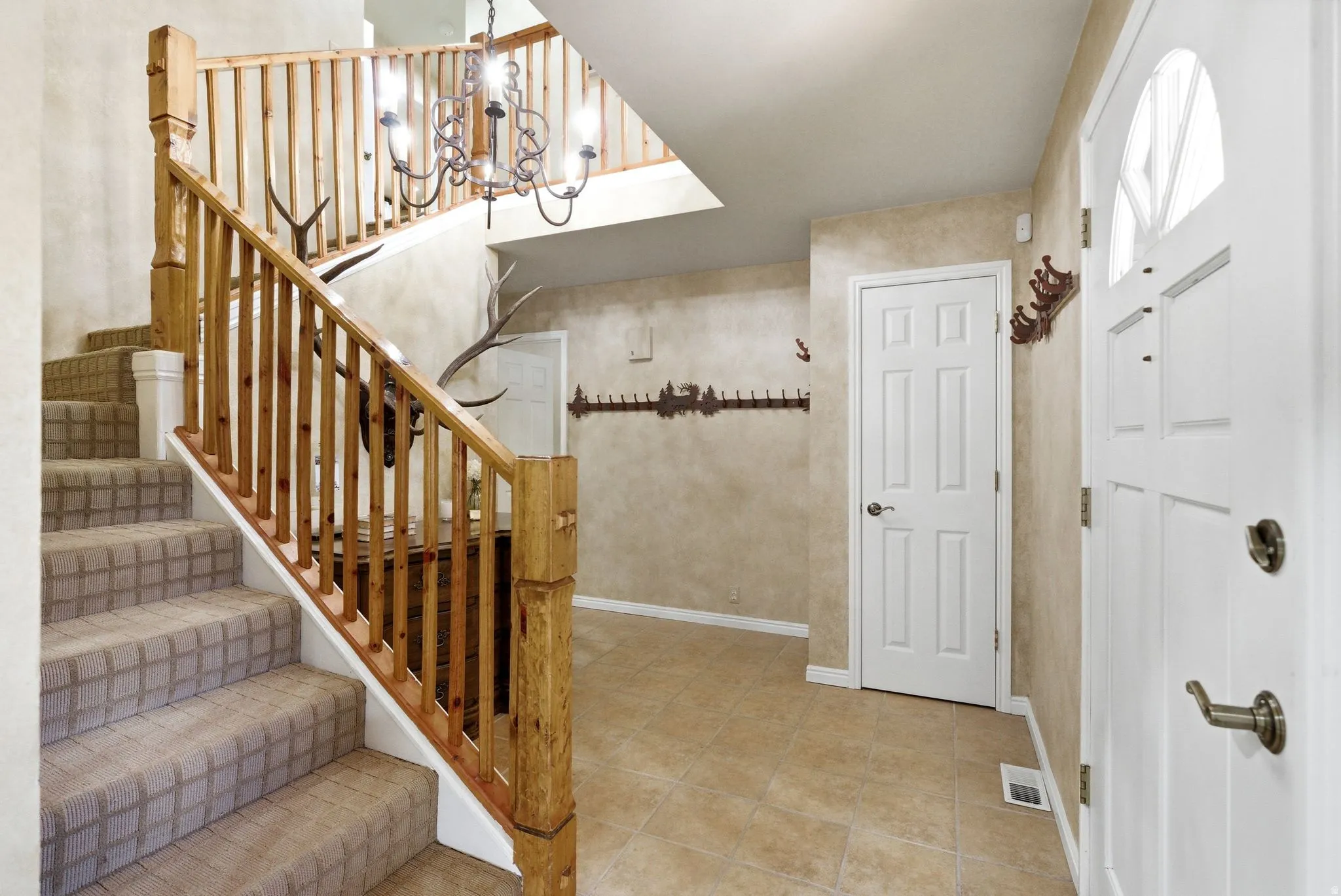 Entry foyer featuring a wood-finish staircase with carpeted treads and natural wood balusters
