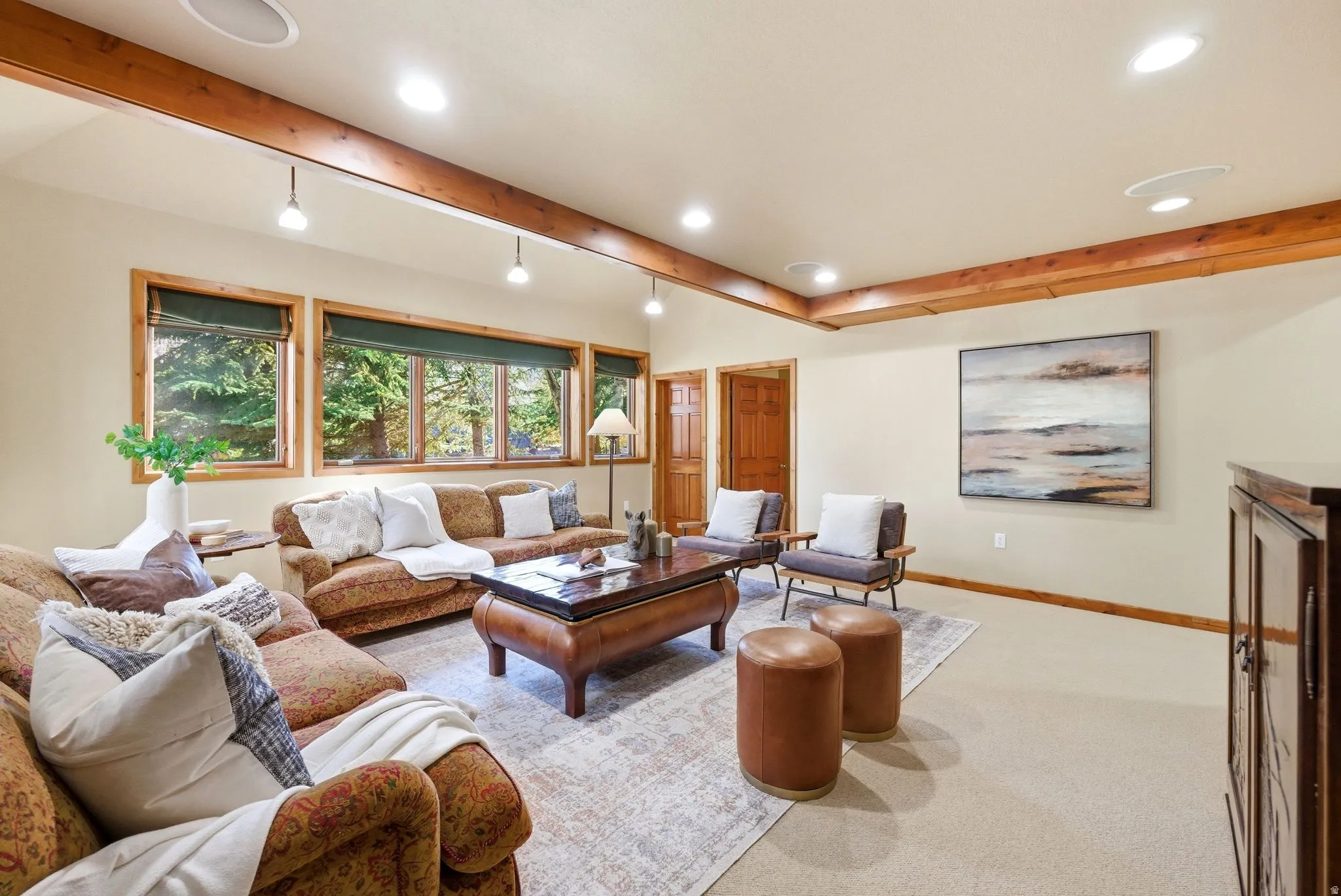 Expansive living area with wood-finish ceiling beams, recessed lighting, and wall-mounted track lighting