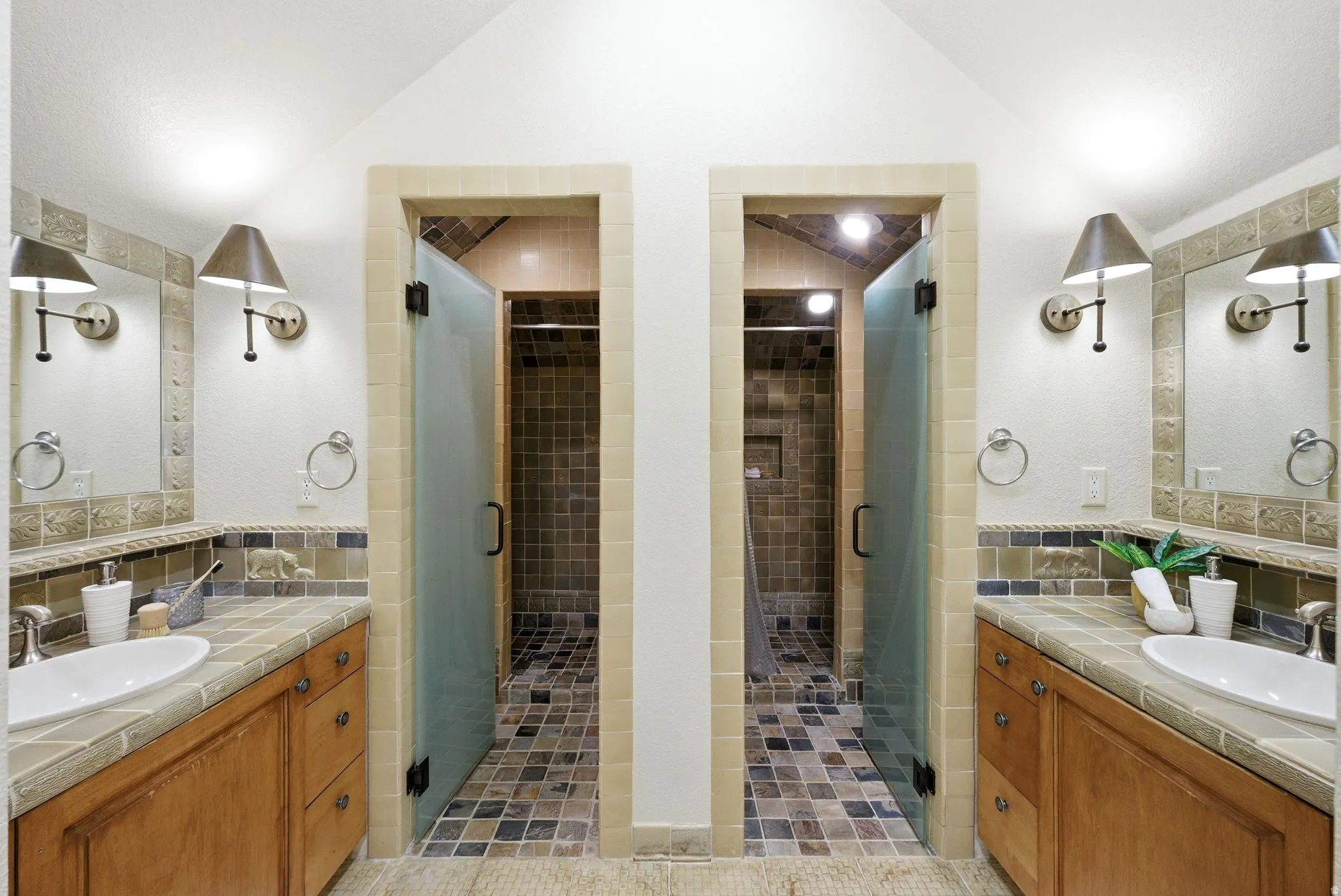 Dual vanity bathroom featuring individual tiled showers with glass doors