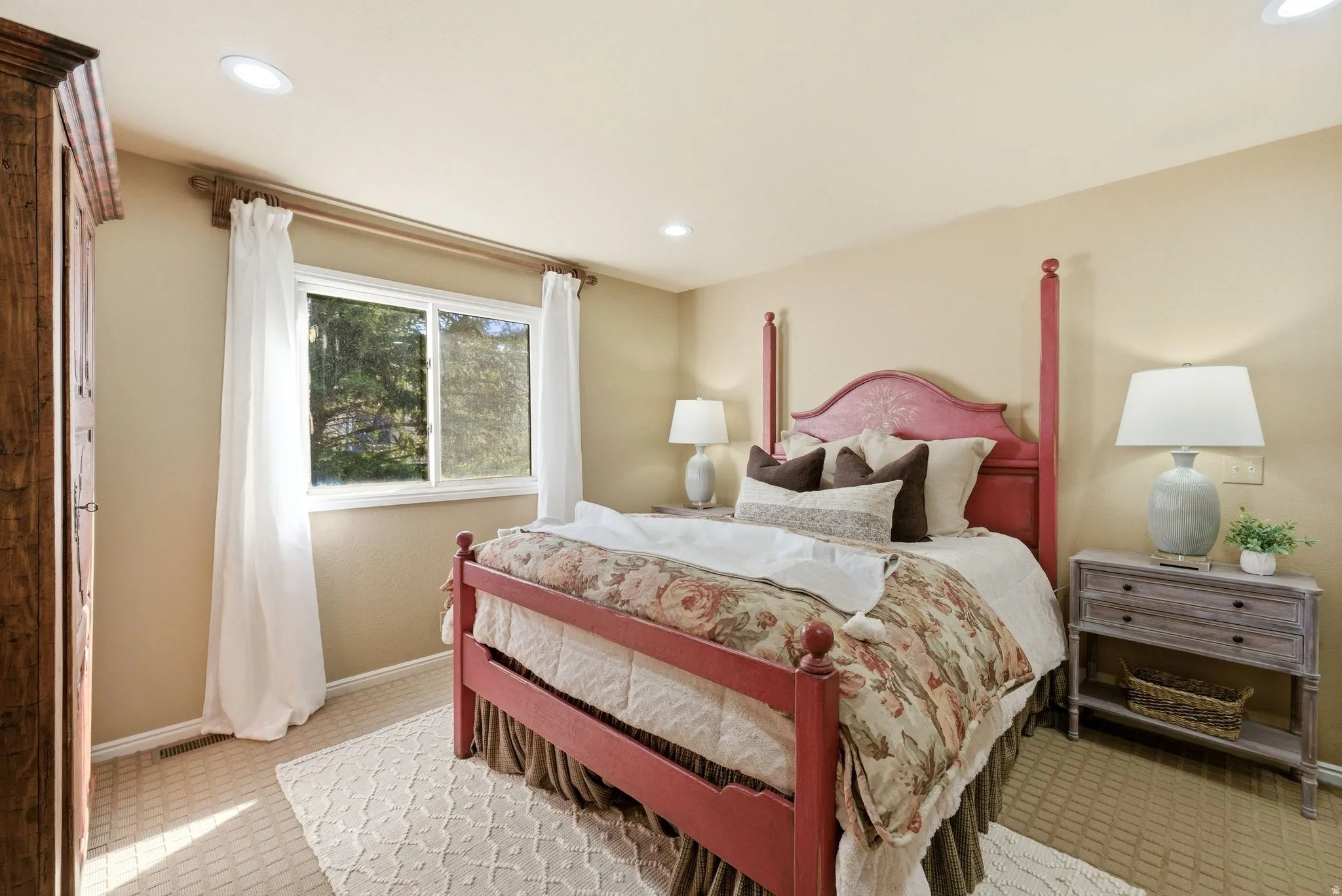 Recessed lighting illuminates this room featuring a large window, neutral wall paint, and textured carpeting