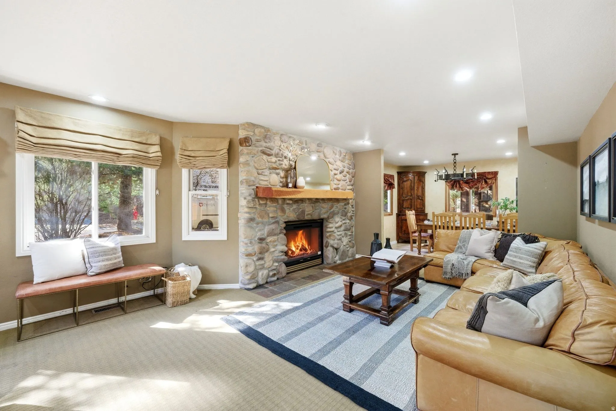 Spacious living area featuring a stone fireplace with a wood mantle, recessed lighting, and multiple windows