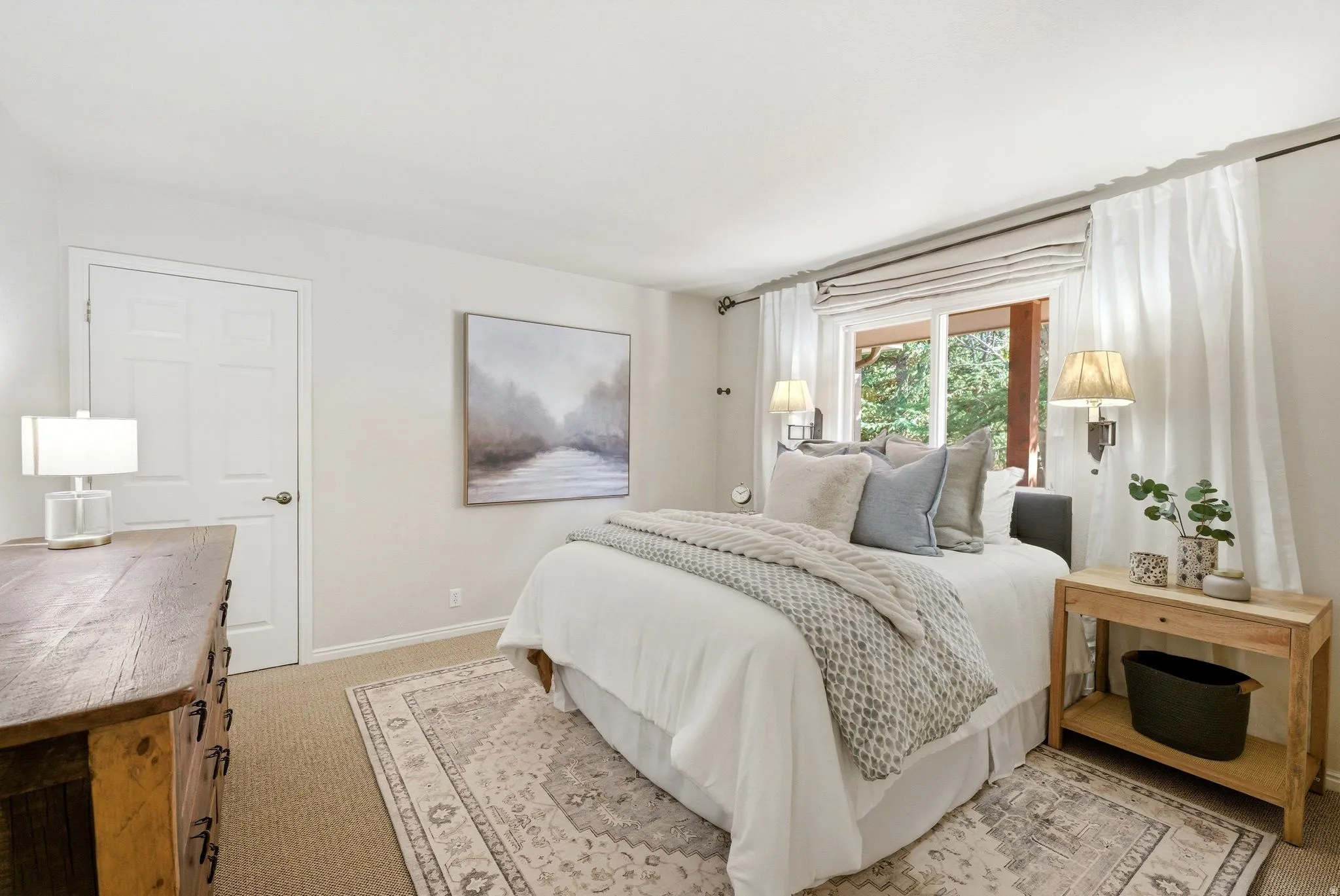 Carpeted bedroom with a large window, a solid panel door, and wall-mounted sconces