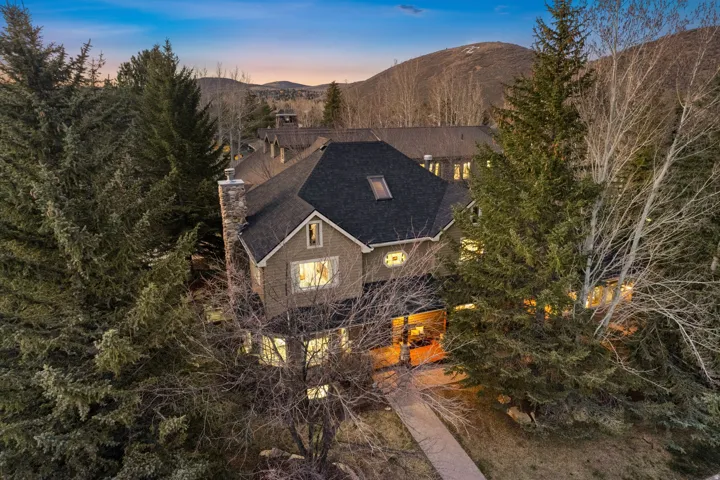 Contemporary multi-story residence with a dark shingle roof and a prominent stone chimney