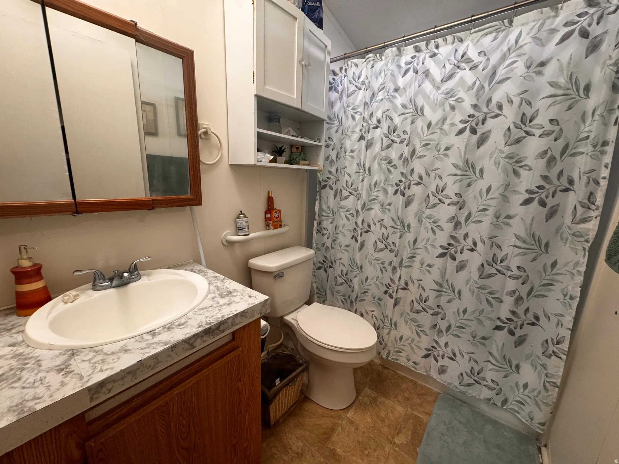 Full bathroom featuring a vanity with a white oval sink, a wood-finish cabinet, and a countertop with a grey and white pattern