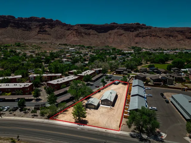 Aerial view showcasing a property with a gray-sided structure and a detached outbuilding