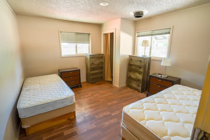 Room featuring wood-finish flooring, two windows with blinds, and a built-in recessed ceiling light fixture
