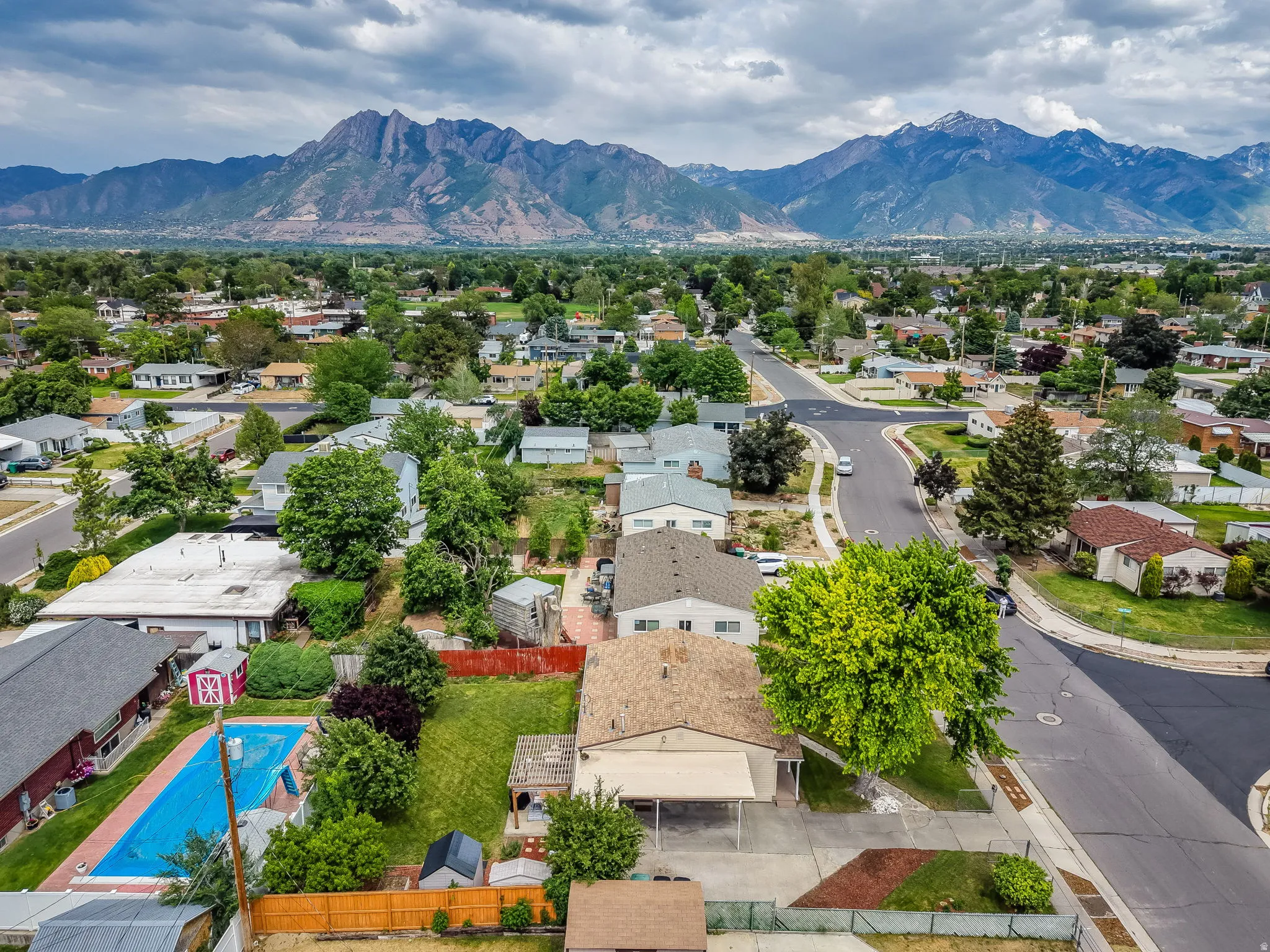 Residential neighborhood with mature trees and mountain backdrop