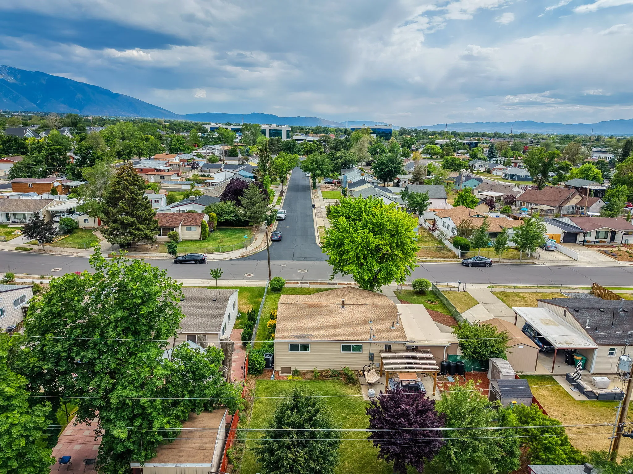 Residential neighborhood with a mountain backdrop, mature trees, paved streets, and single-family homes