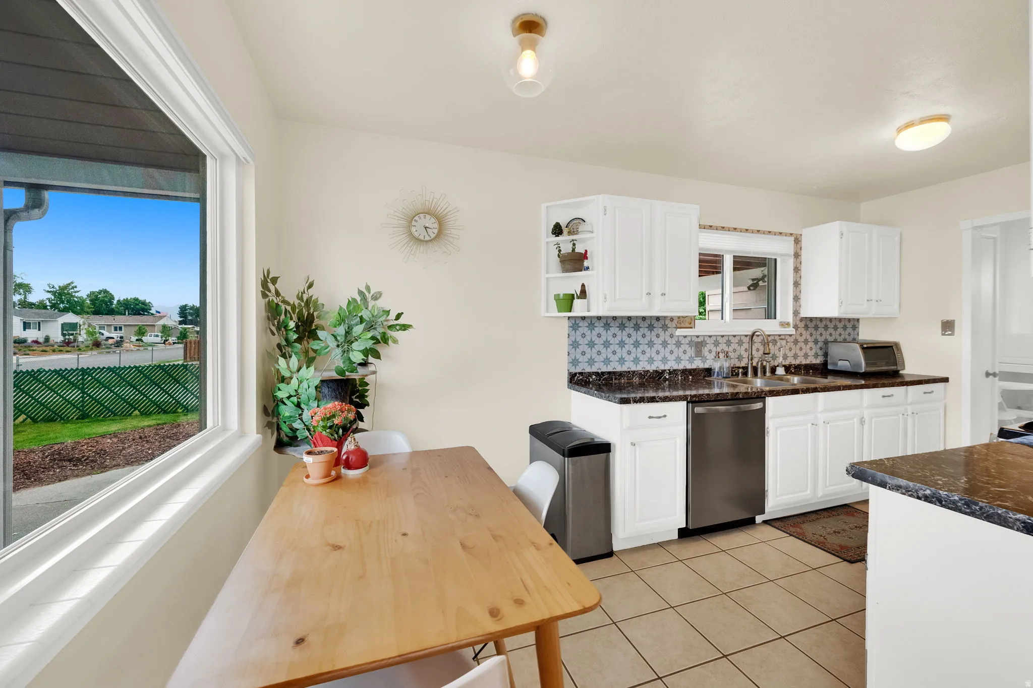 Kitchen area featuring white cabinetry with dark countertops, stainless steel appliances, and a tiled backsplash