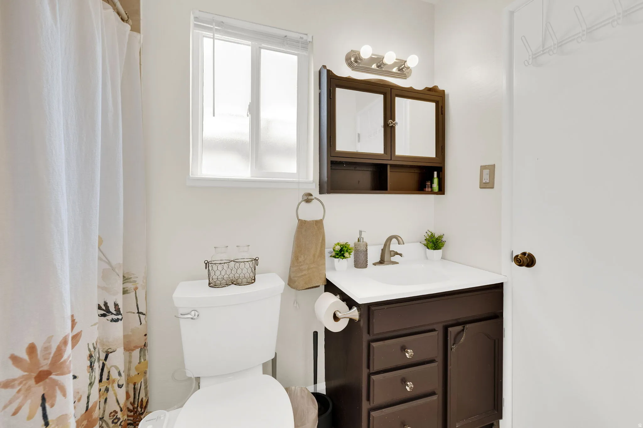 Full bathroom featuring a white toilet, single vanity with a dark wood-finish base, white countertop, and integrated sink