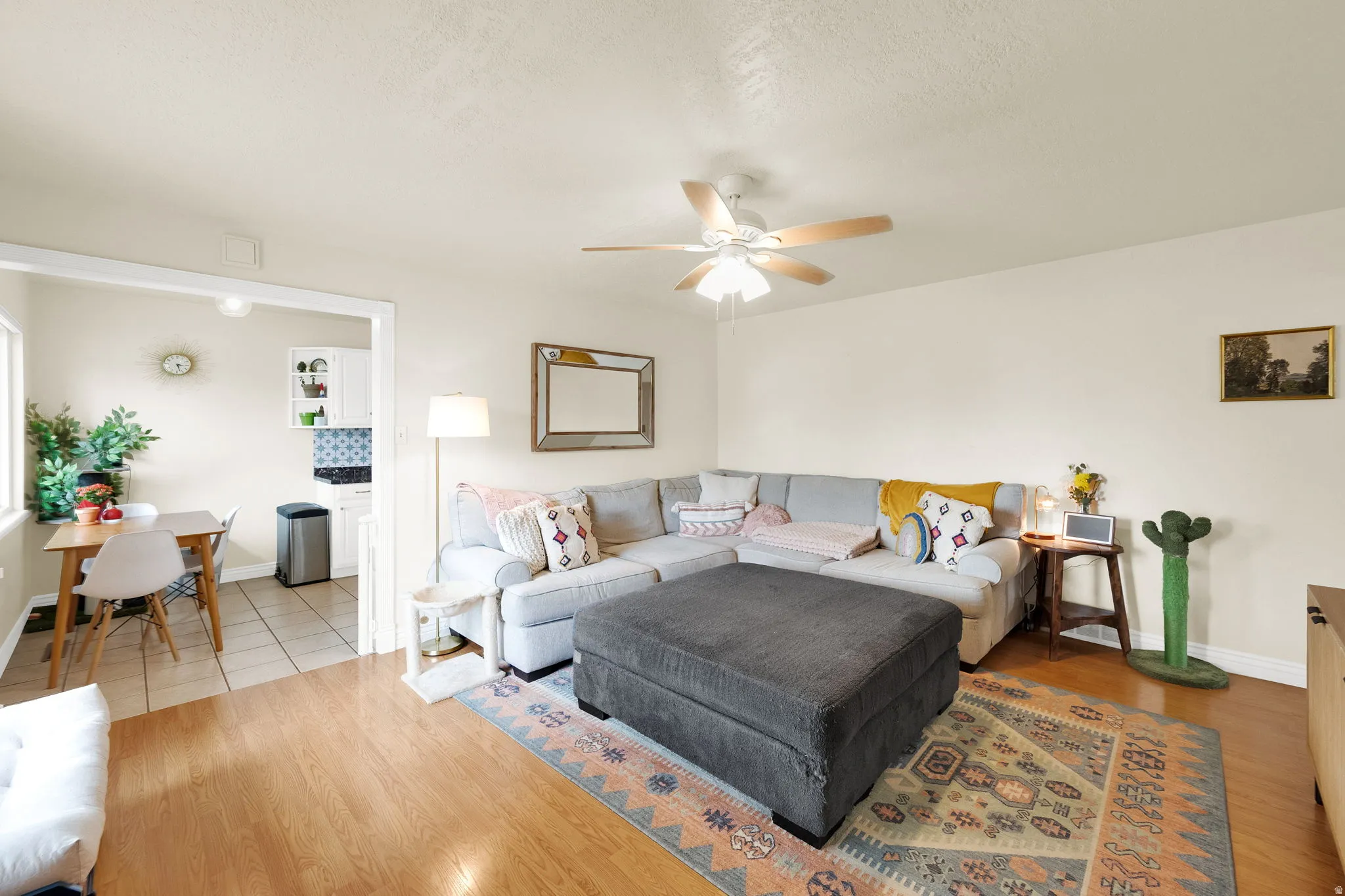 Living area featuring wood-finish flooring, a ceiling fan with integrated lighting, and neutral wall tones