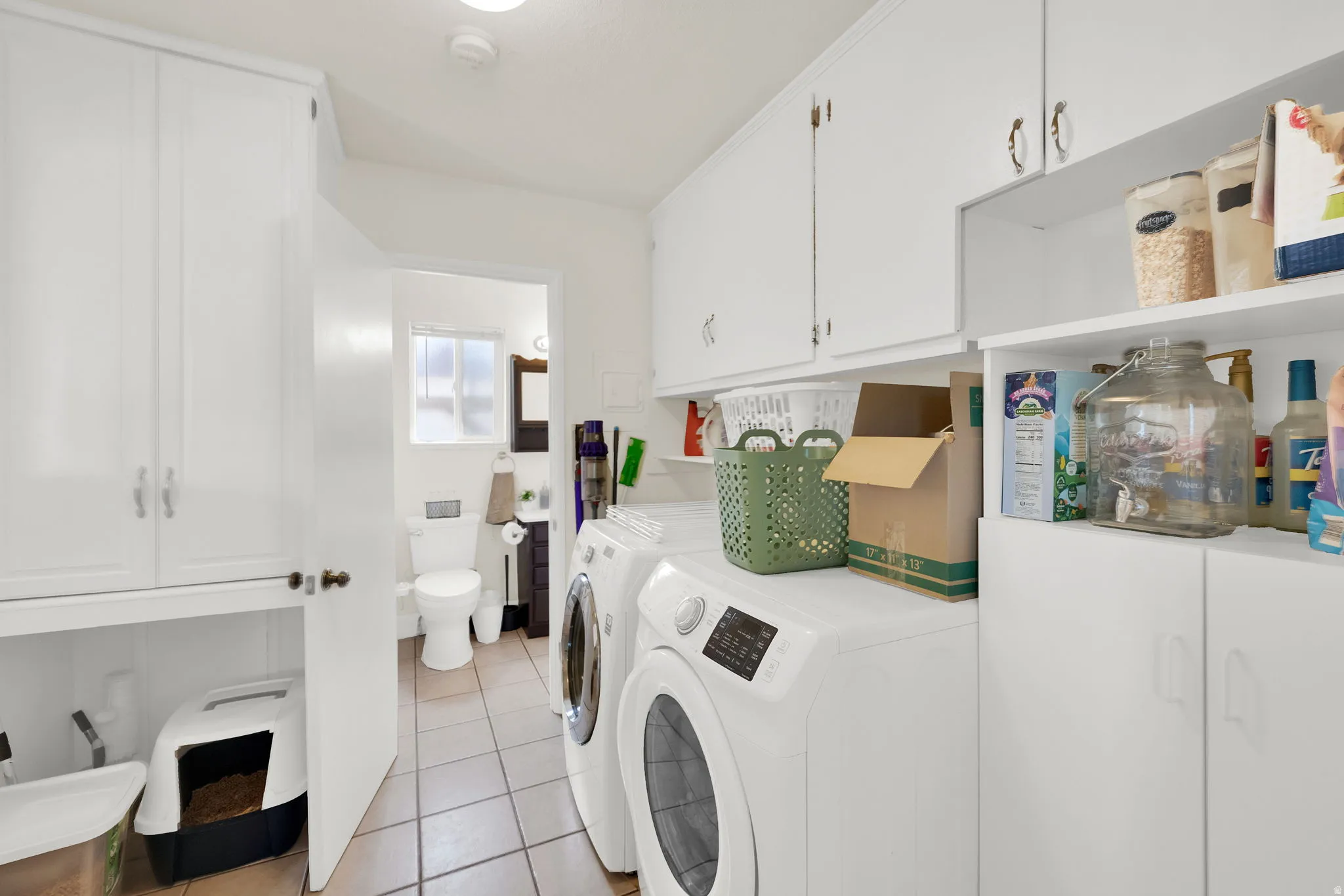Laundry room with white upper and lower cabinetry, open shelving, and tiled flooring