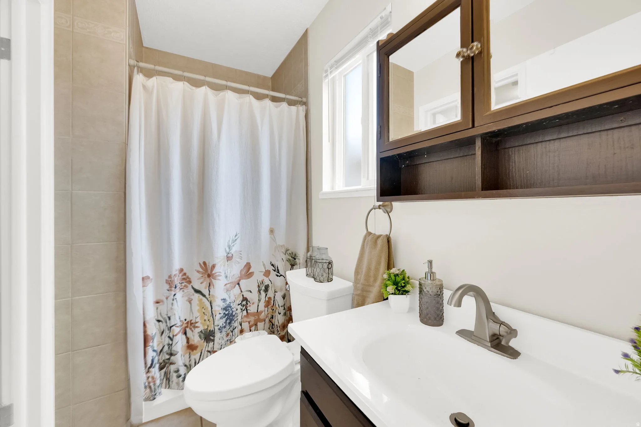 Bathroom featuring a white ceramic toilet, a vanity with a white sink, and a dark wood-finish medicine cabinet