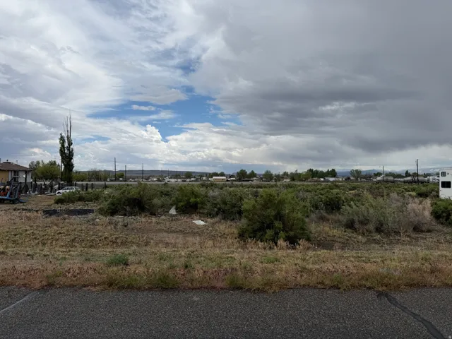 Expansive undeveloped lot featuring natural shrubbery and a clear sky overhead