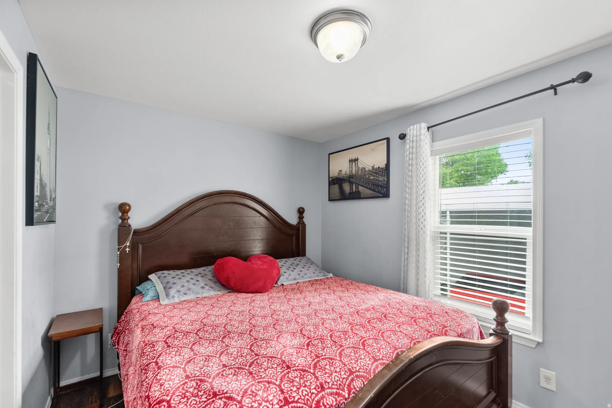 Bedroom featuring light gray wall paint, wood-finish flooring, and a single window with white blinds