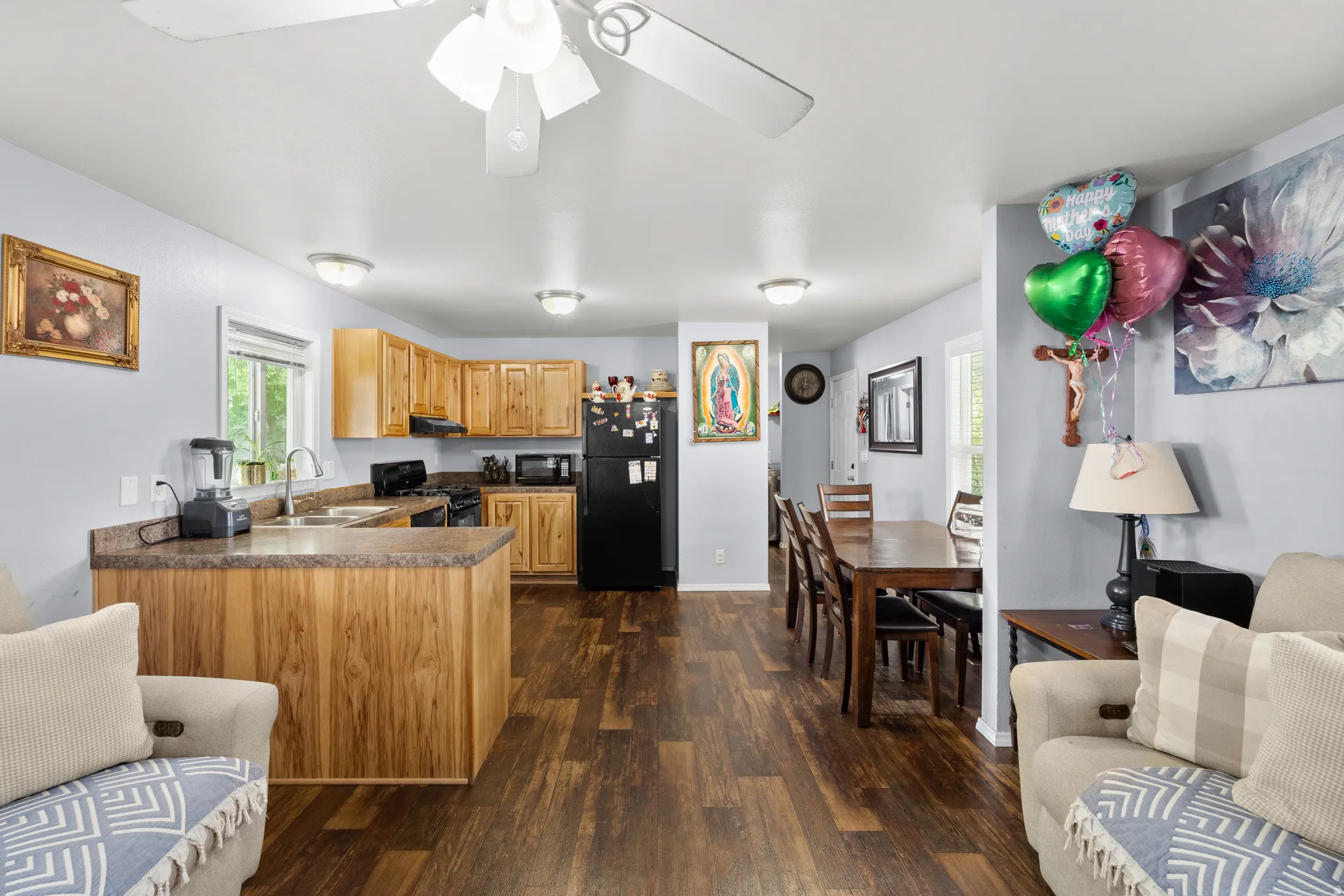 Open-concept living space featuring wood-finish flooring, a kitchen with natural wood cabinetry and a peninsula, and recessed lighting