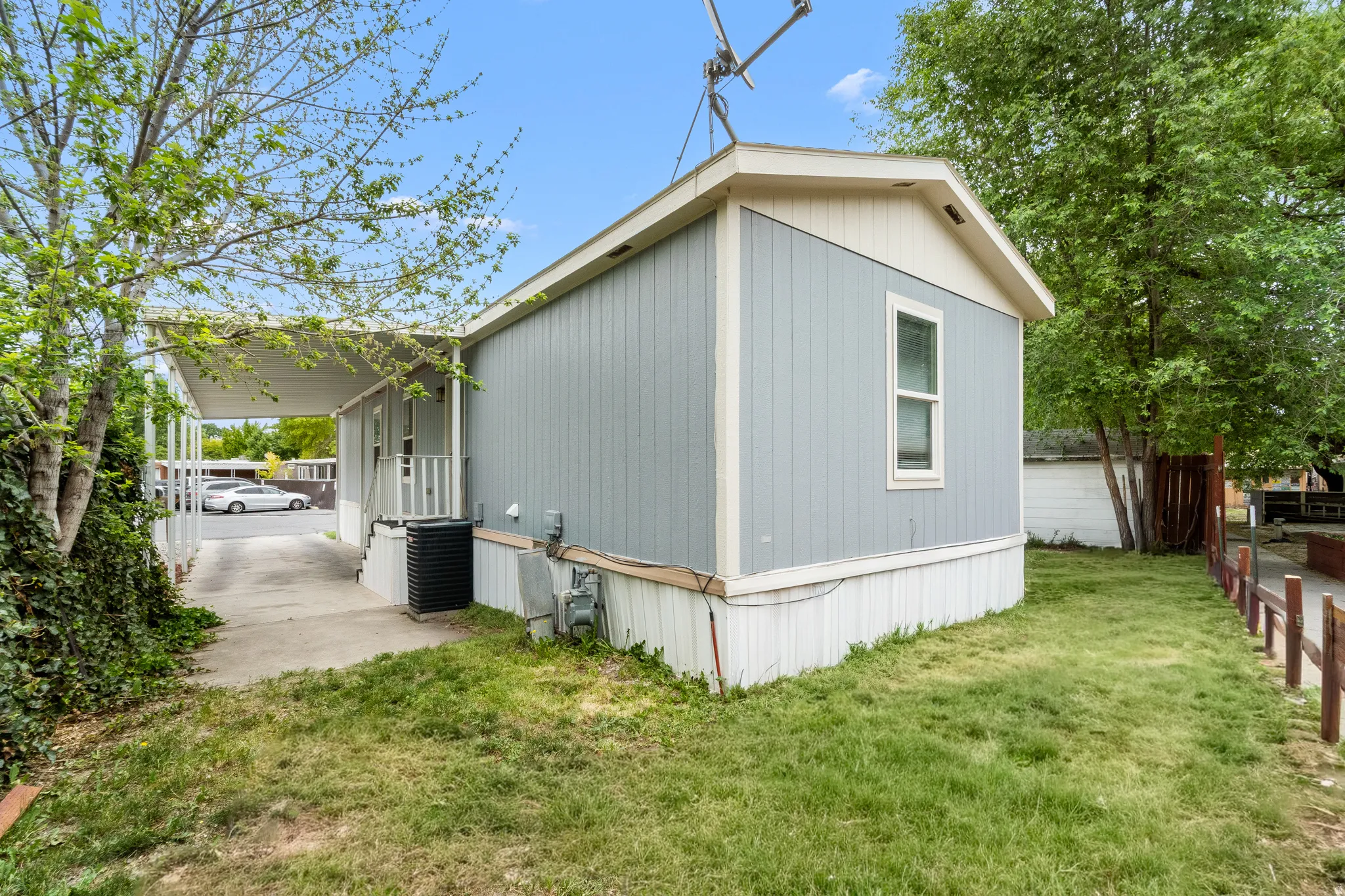 Light blue siding exterior with white trim and a covered carport