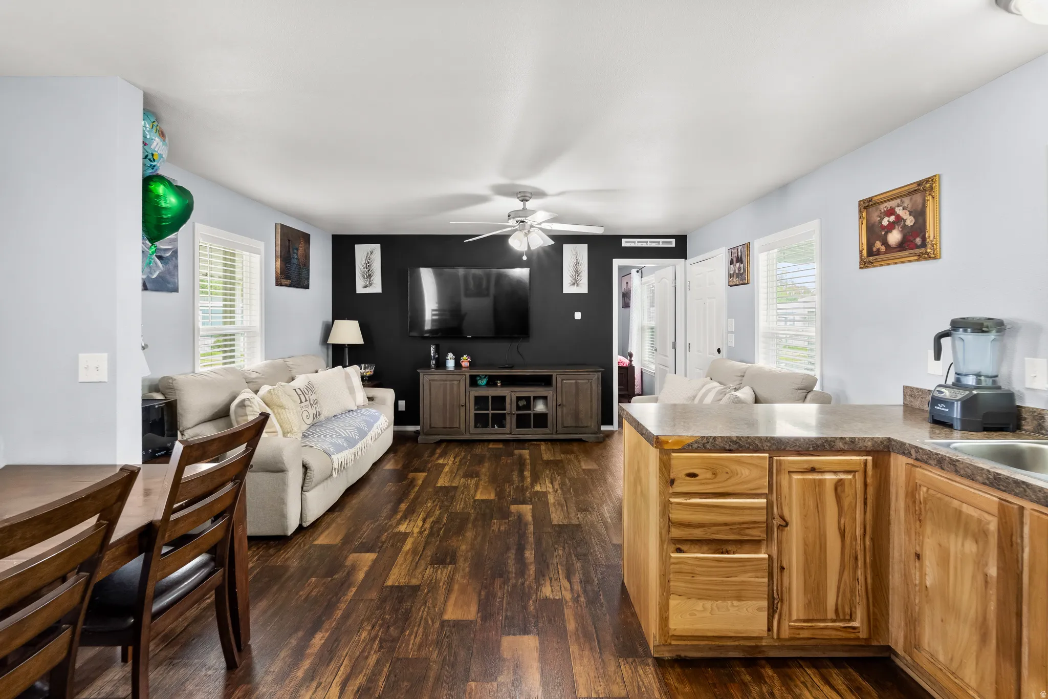 Open-concept living area with wood-finish flooring, a ceiling fan, and light blue walls