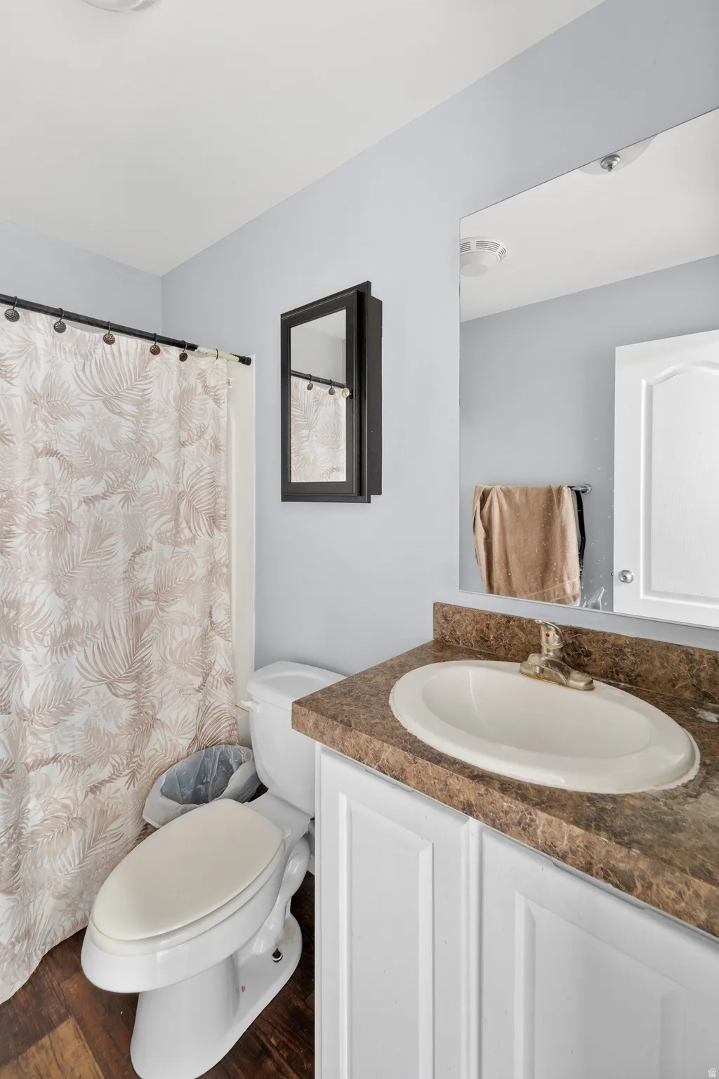 Bathroom featuring a white vanity with a tan countertop, an integrated oval sink, and a framed mirror