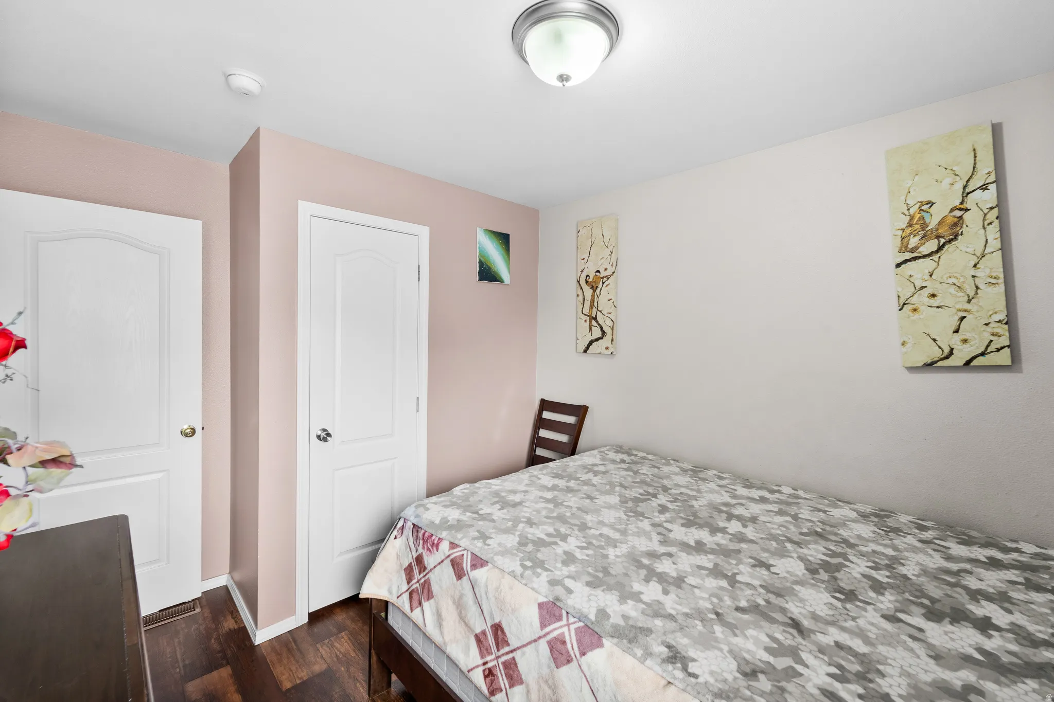 Room featuring wood-finish flooring, two panel-style doors, and a flush mount ceiling light fixture