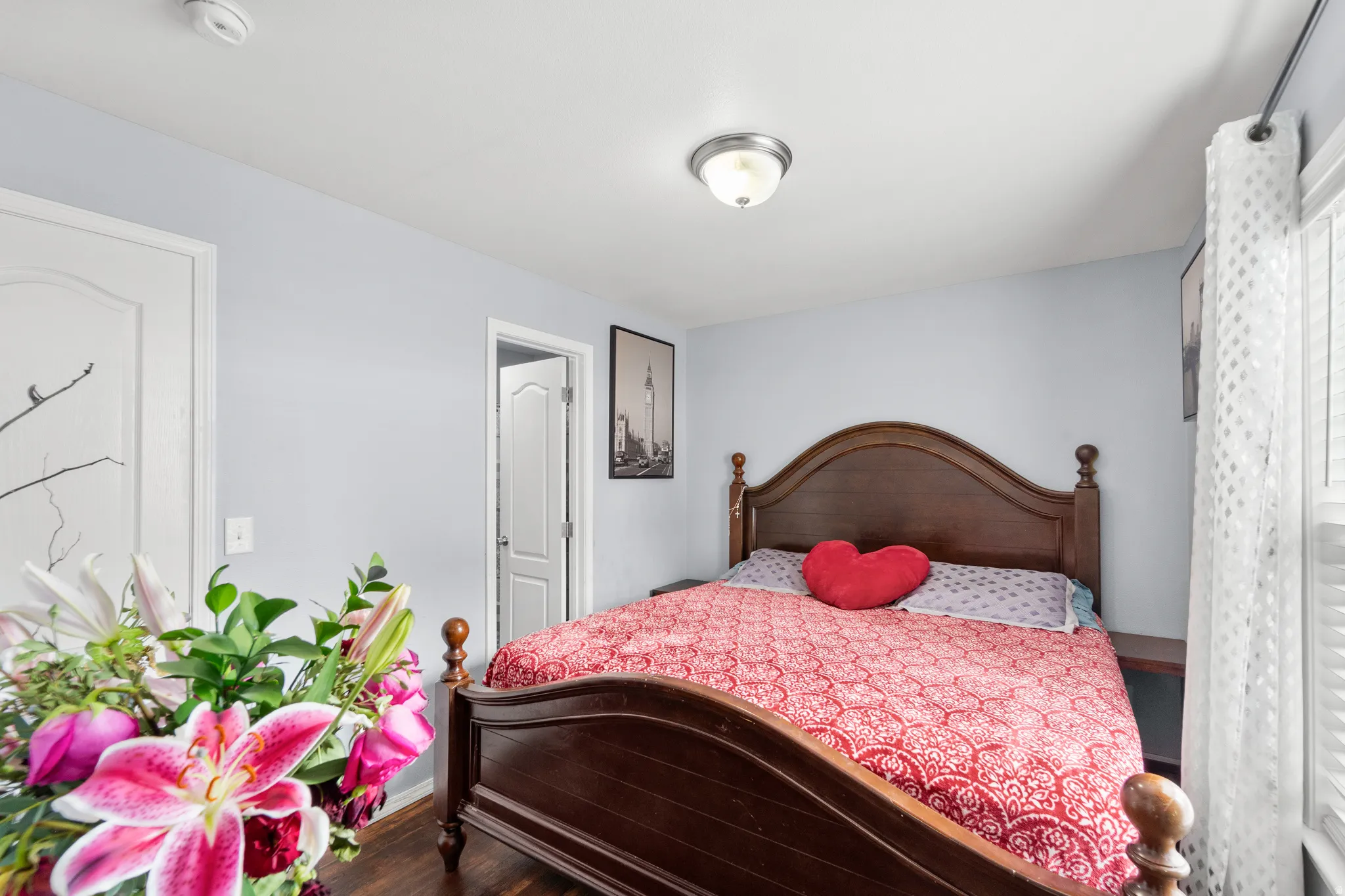 Spacious room featuring wood-finish flooring, light blue wall paint, a ceiling-mounted flush light fixture, and a window with white blinds