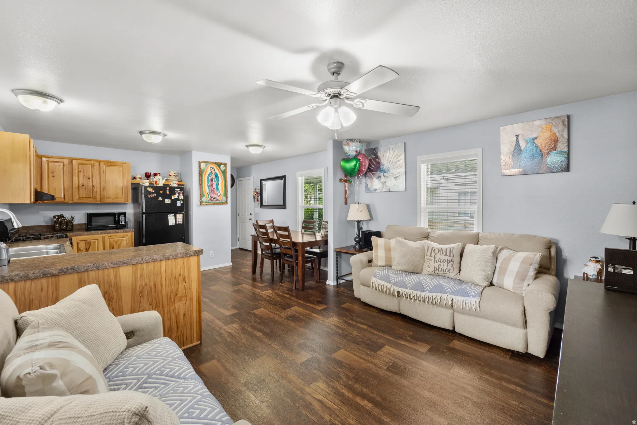 Open-concept living space featuring wood-finish flooring, a kitchen with natural wood cabinetry, a breakfast bar, and a dining area