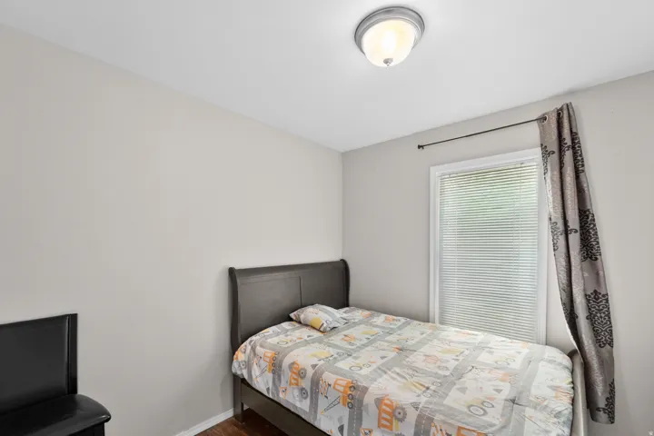 Neutral toned walls with a single window featuring horizontal blinds