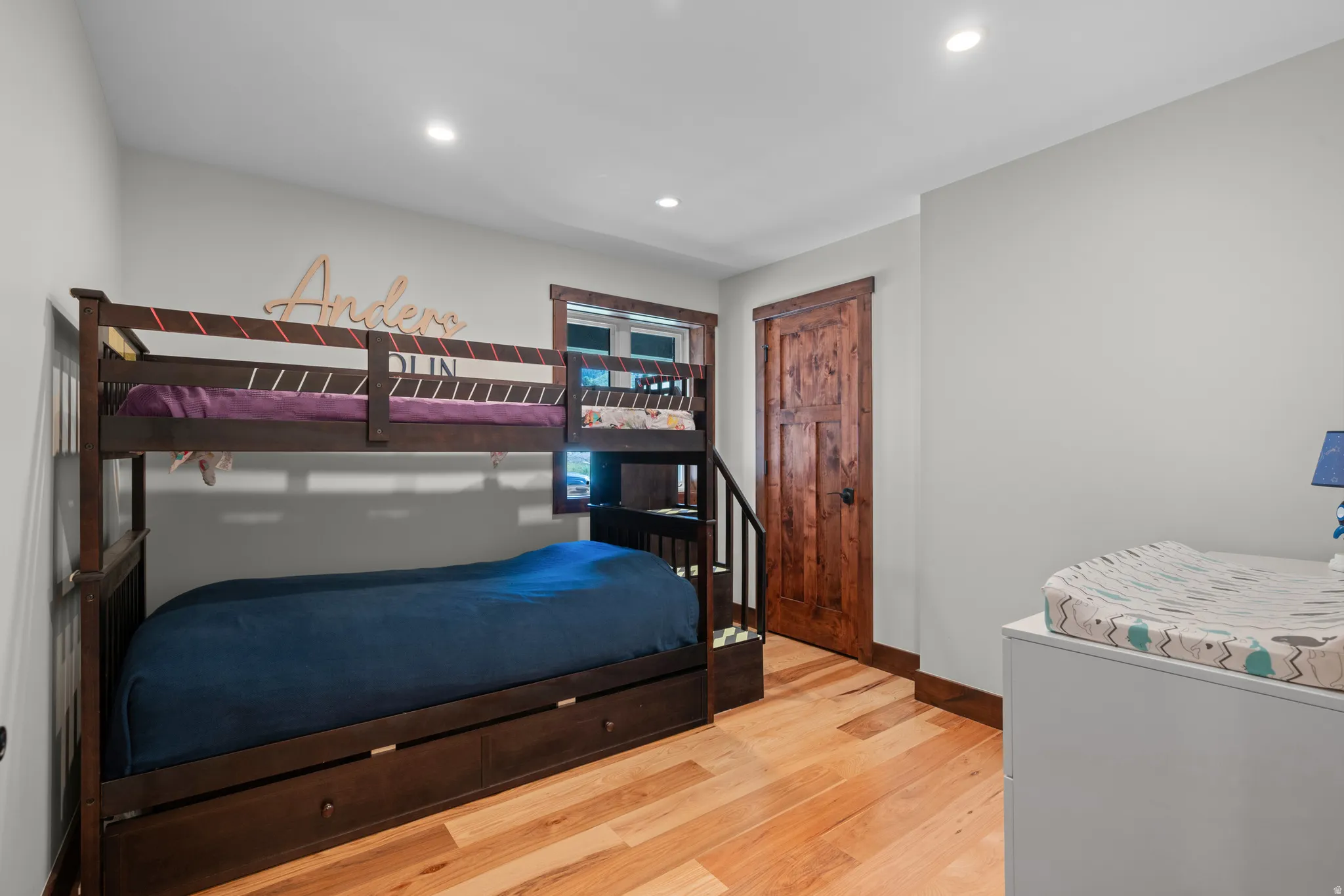 Interior room featuring wood-finish flooring, a solid wood paneled door, and recessed lighting