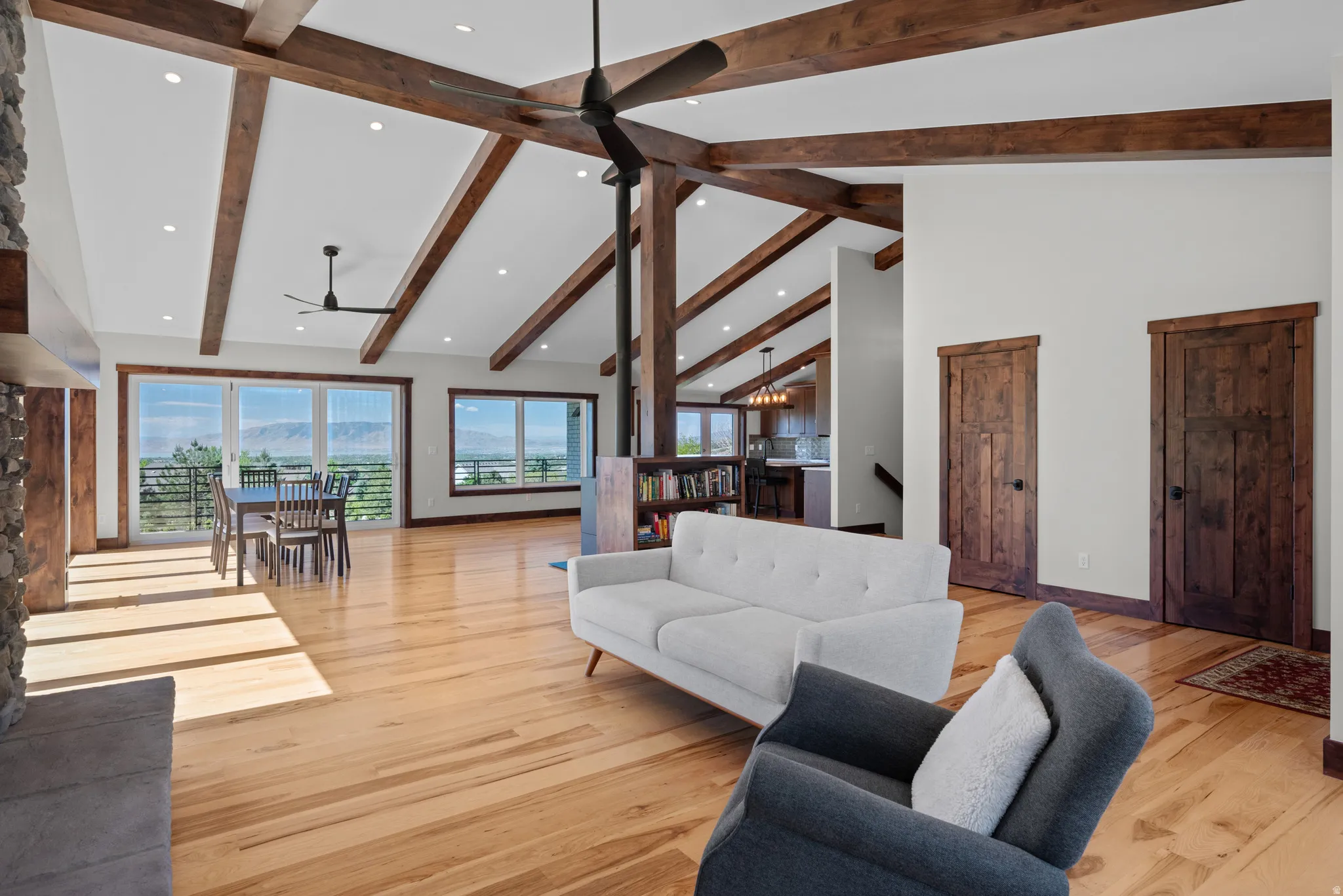 Open-concept living area featuring exposed wood beams, vaulted ceilings, recessed lighting, and light wood-finish flooring
