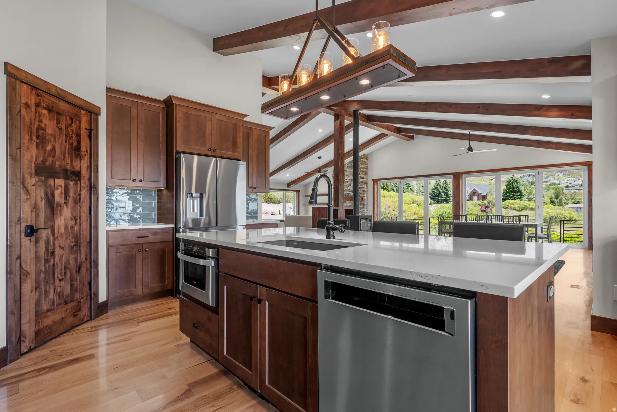 Spacious kitchen featuring an expansive island with a white countertop, wood-finish flooring, full-height cabinetry, and stainless steel appliances