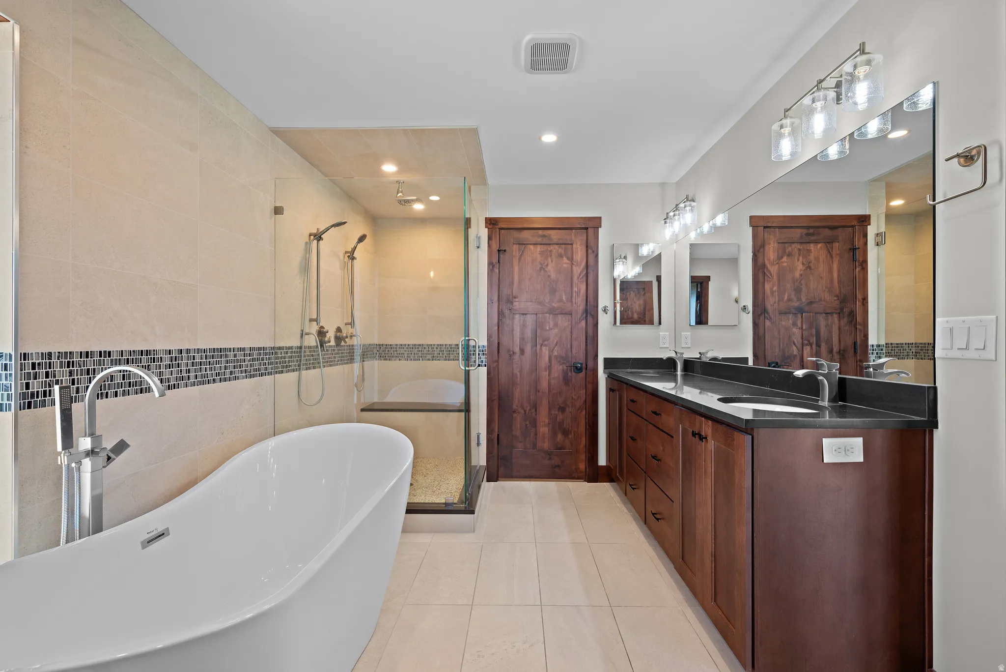 Modern bathroom featuring a freestanding soaking tub, glass-enclosed shower with dual showerheads, and light-toned floor tiling