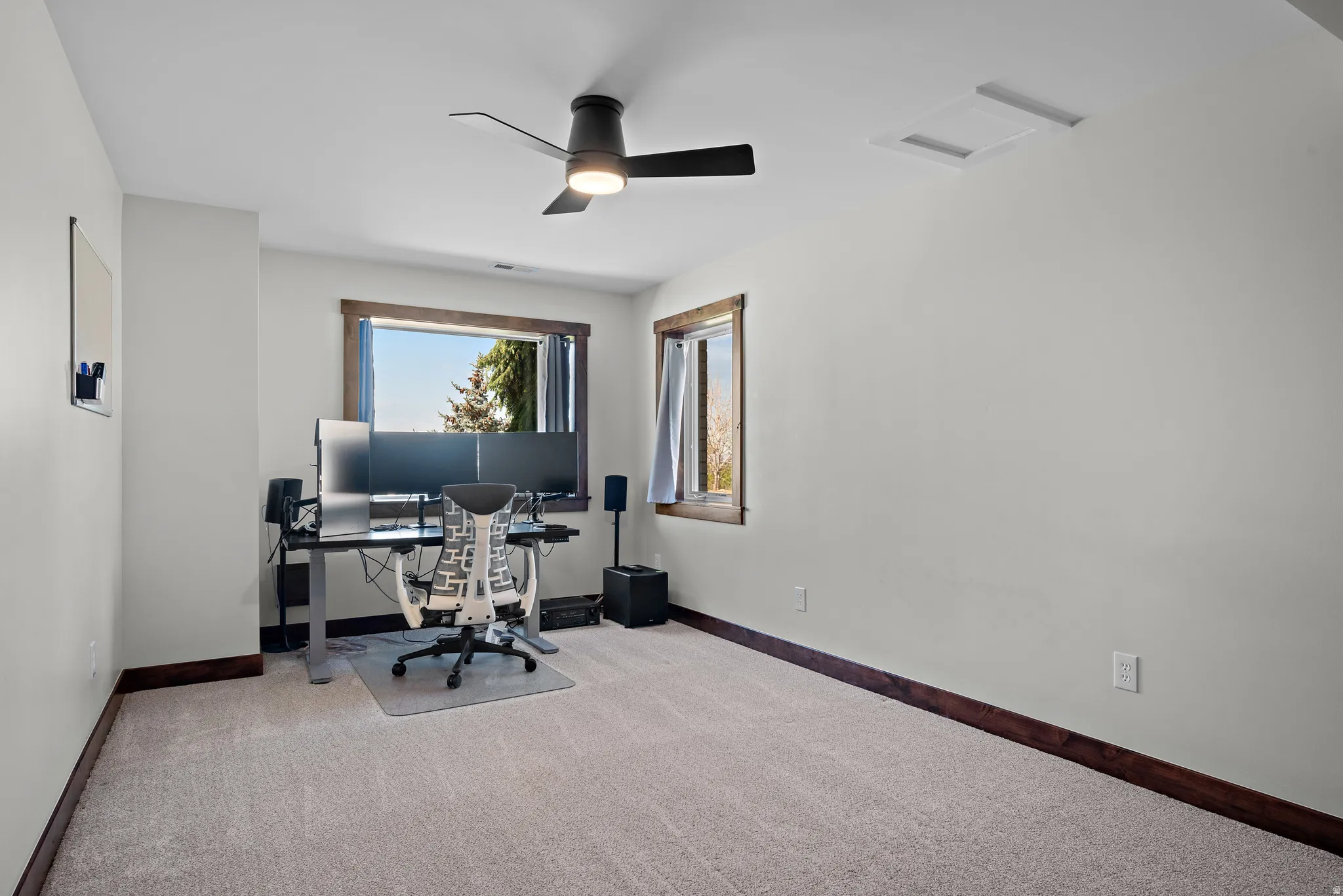 Carpeted room with a ceiling fan light fixture and a window featuring wood trim