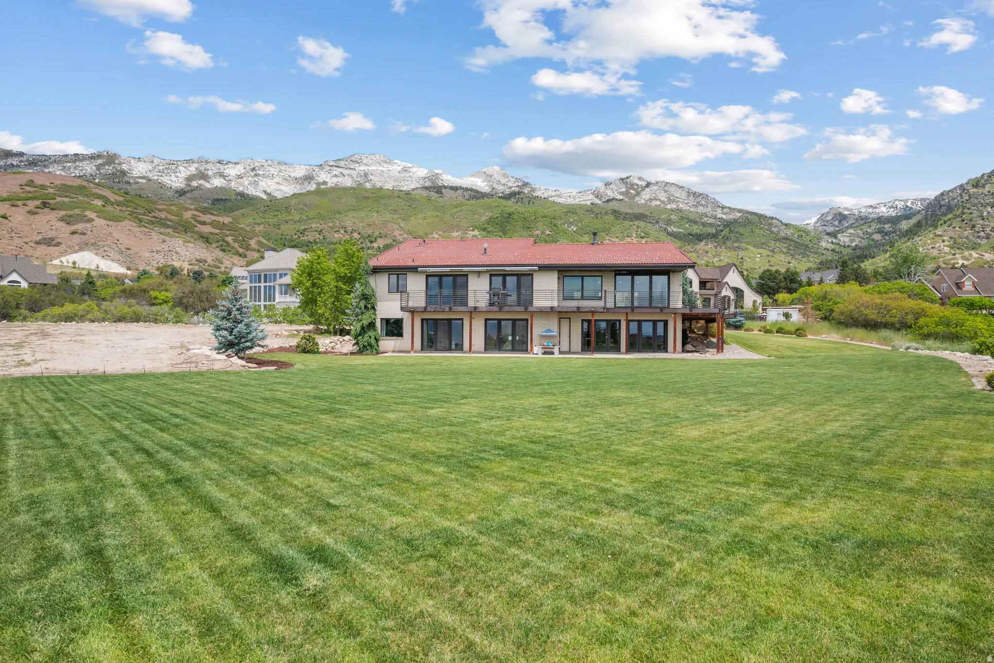 Expansive rear lawn featuring a two-story residence with multiple balconies and patio access