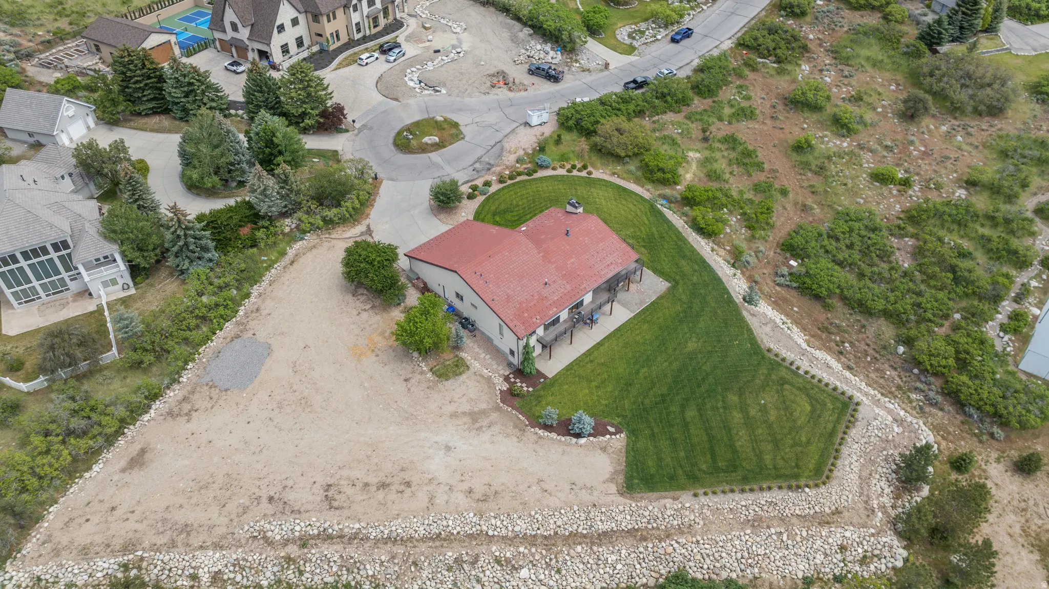 Expansive property featuring a red-roofed residence, a terraced lawn, and a spacious deck