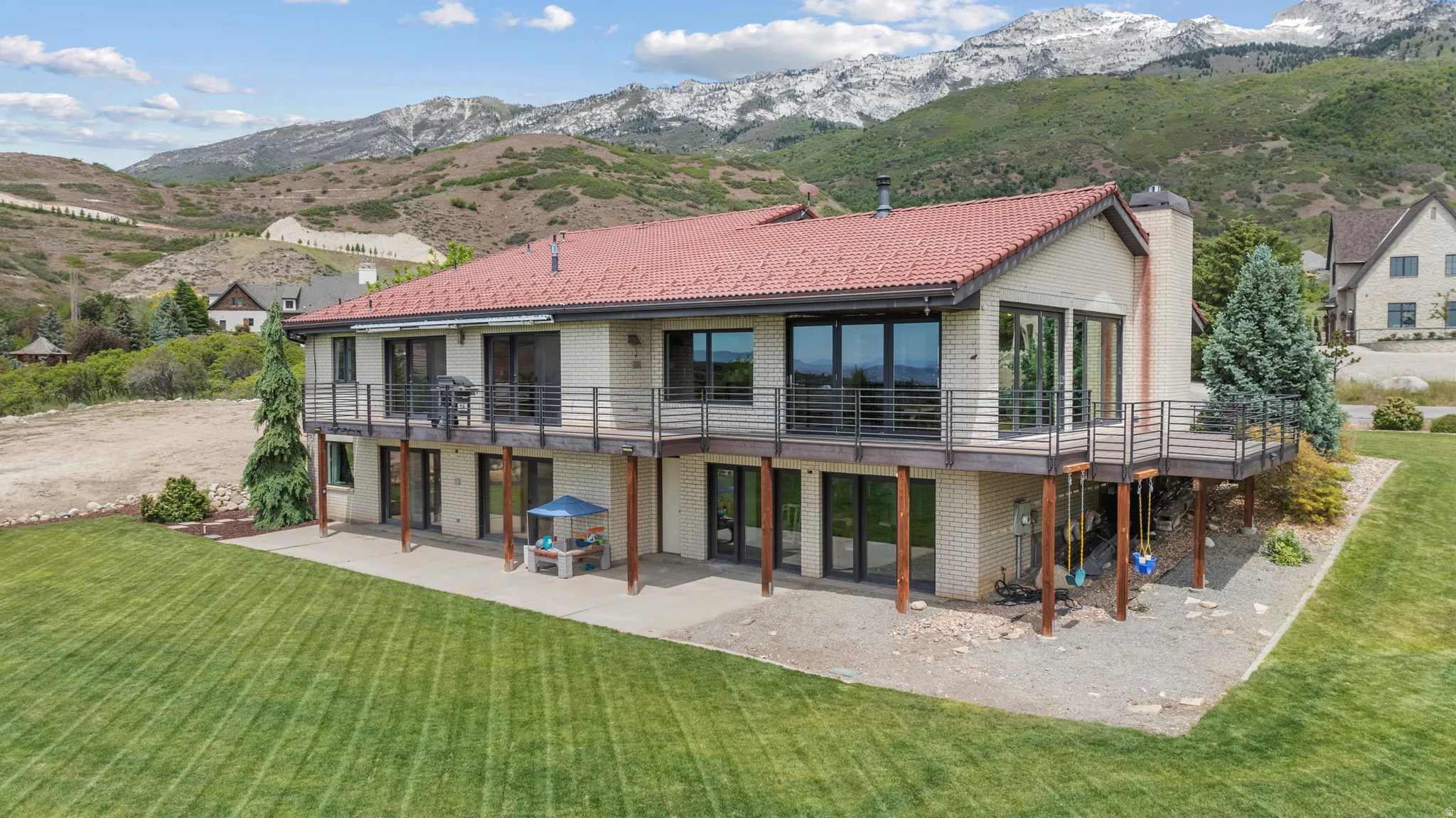 Two-story residence featuring an orange tile roof and beige brick facade