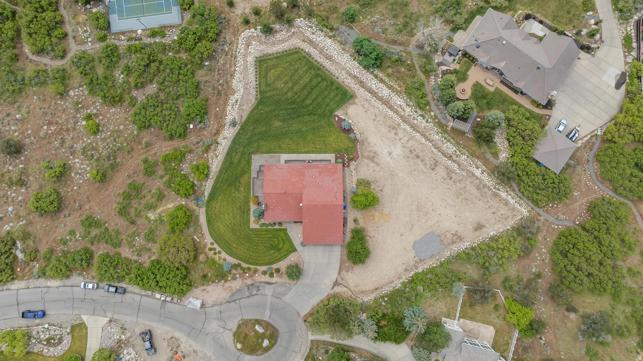 Property featuring a red-roofed residence, a manicured lawn area, and extensive natural landscaping