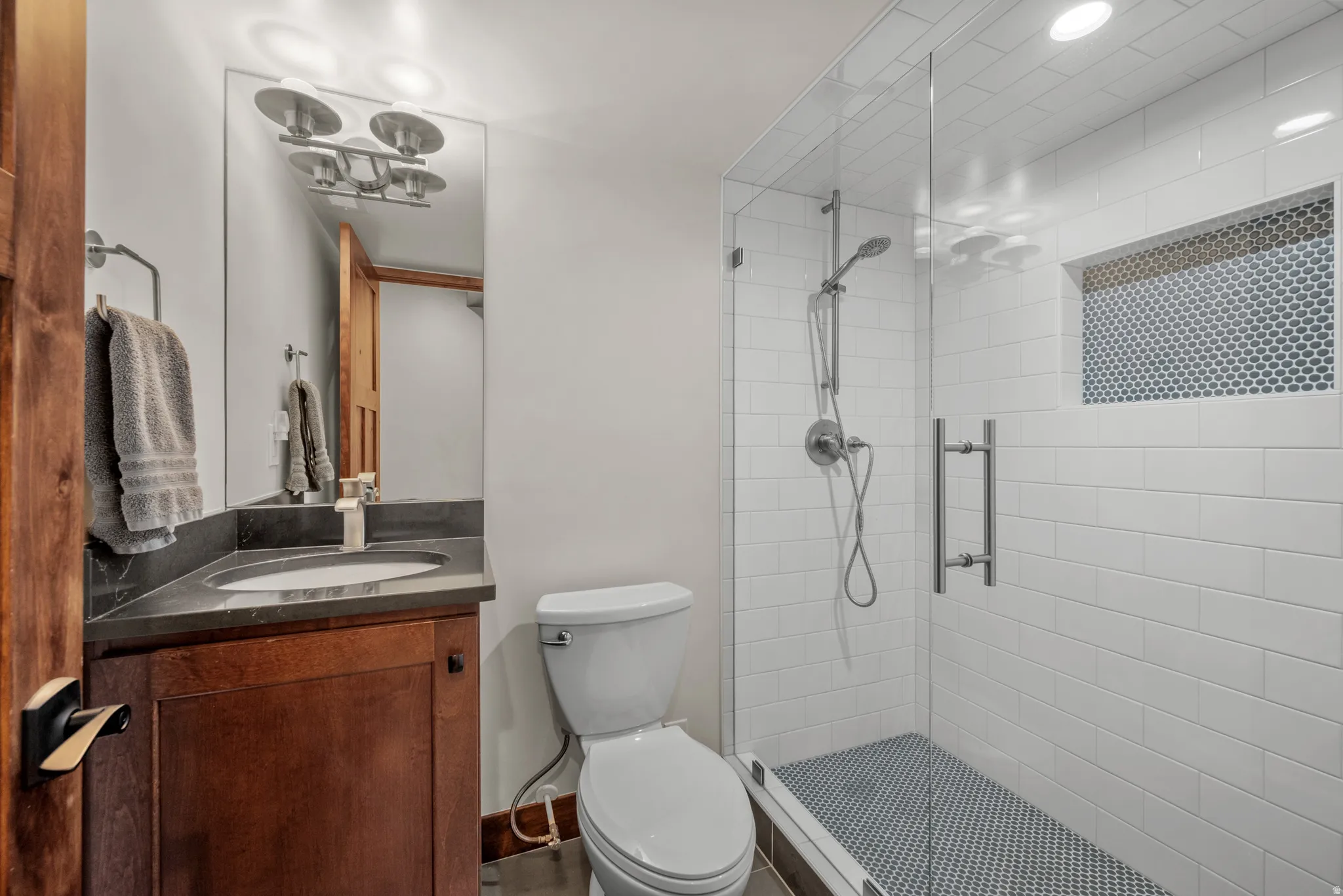 Full bathroom featuring a walk-in shower with clear glass enclosure, white subway tile surround, and an integrated tiled niche