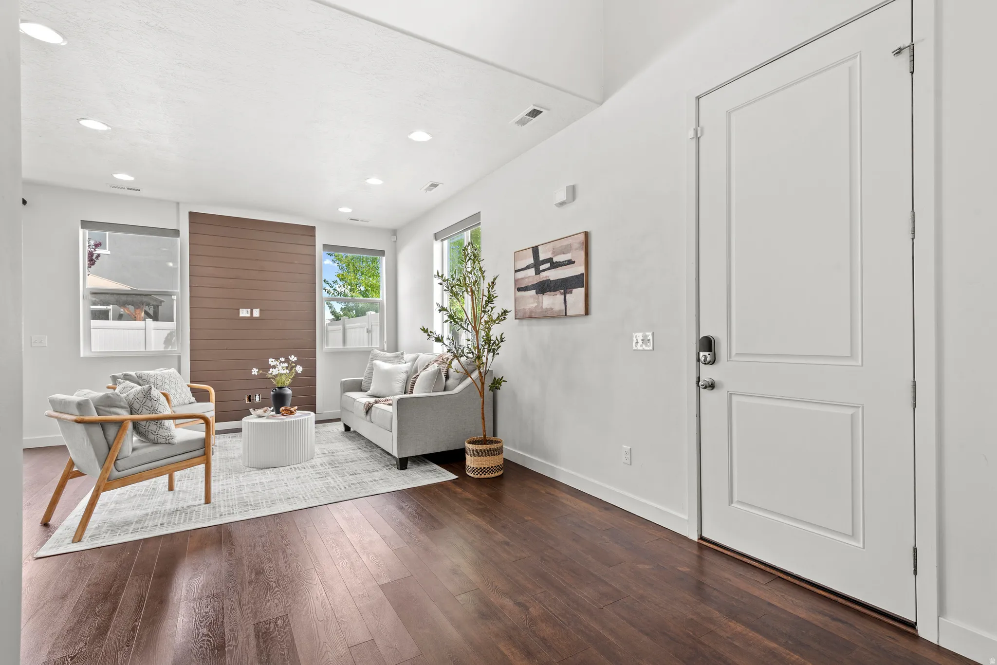 Bright living space featuring dark wood-finish flooring, recessed lighting, and a modern accent wall with horizontal paneling