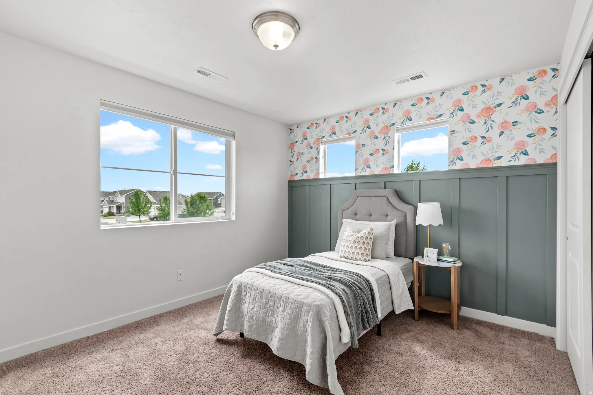 Carpeted room featuring a large window, three smaller transom windows, and a built-in board and batten wall treatment