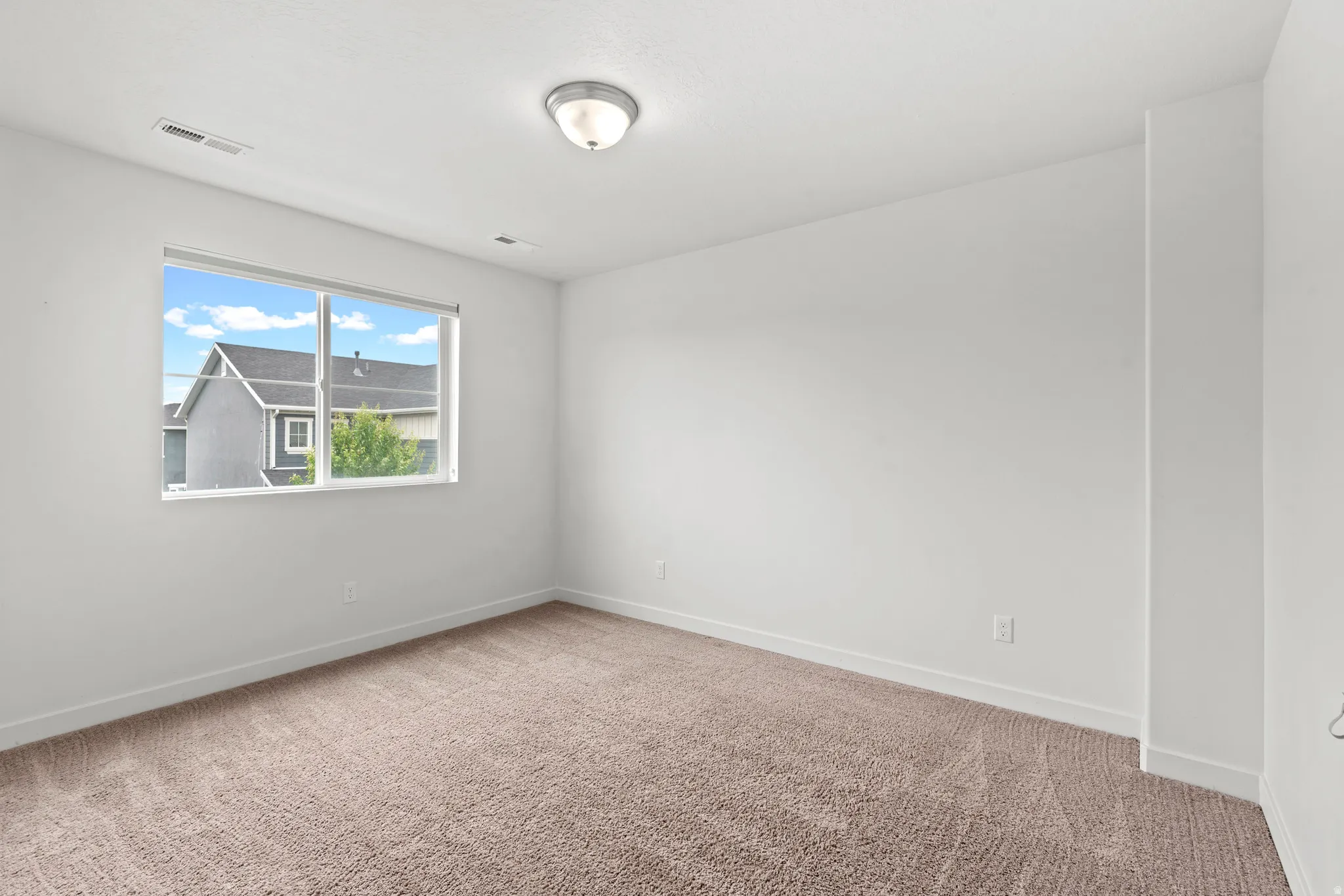 Bright interior space featuring a large window, neutral wall tones, and carpet flooring