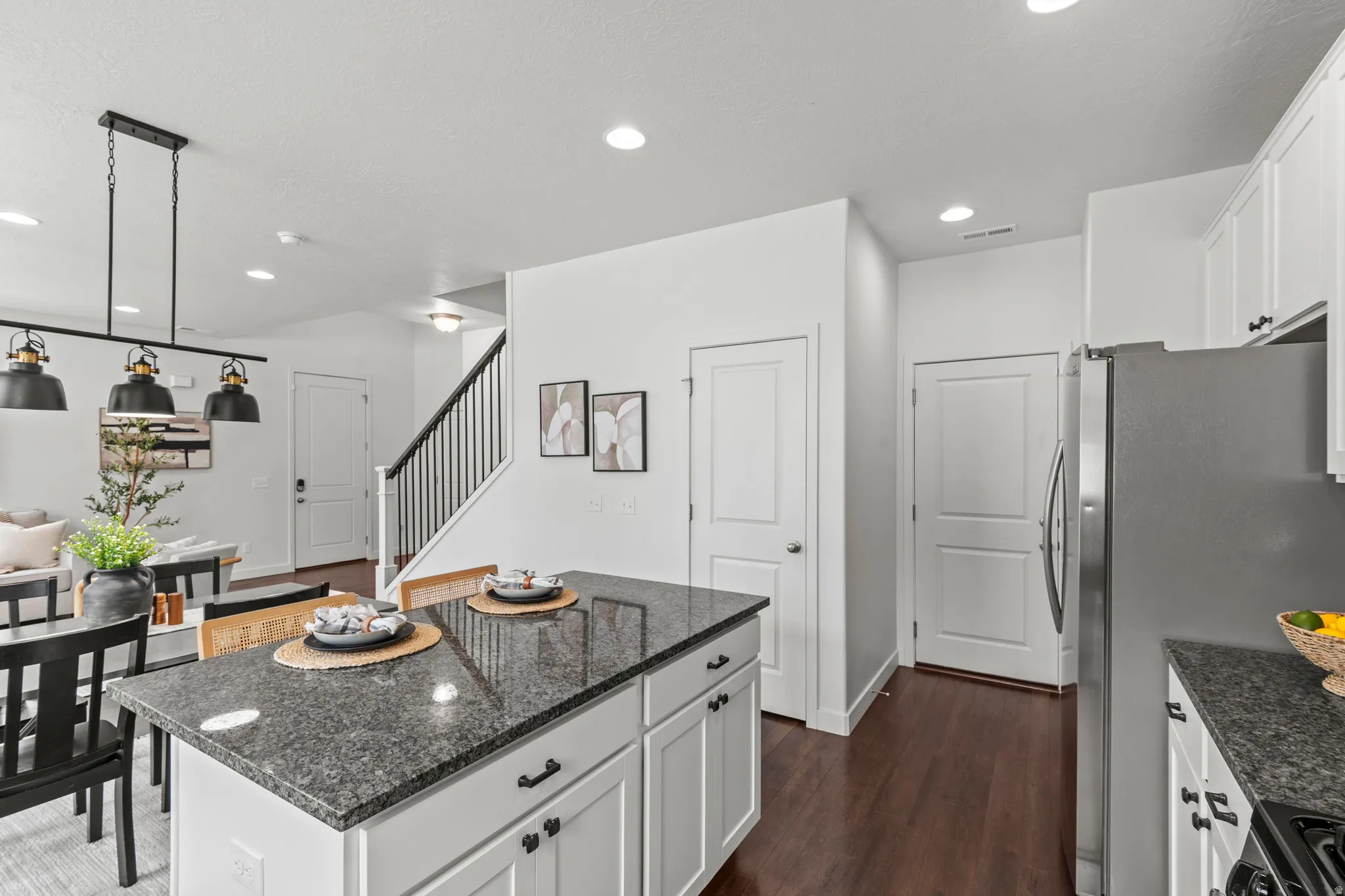 Kitchen island featuring a dark granite countertop and white cabinetry with black hardware