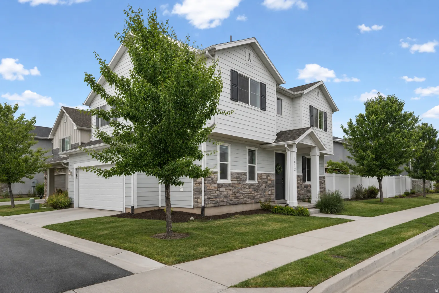 Modern two-story residence featuring light siding, stone accents, and a covered entryway