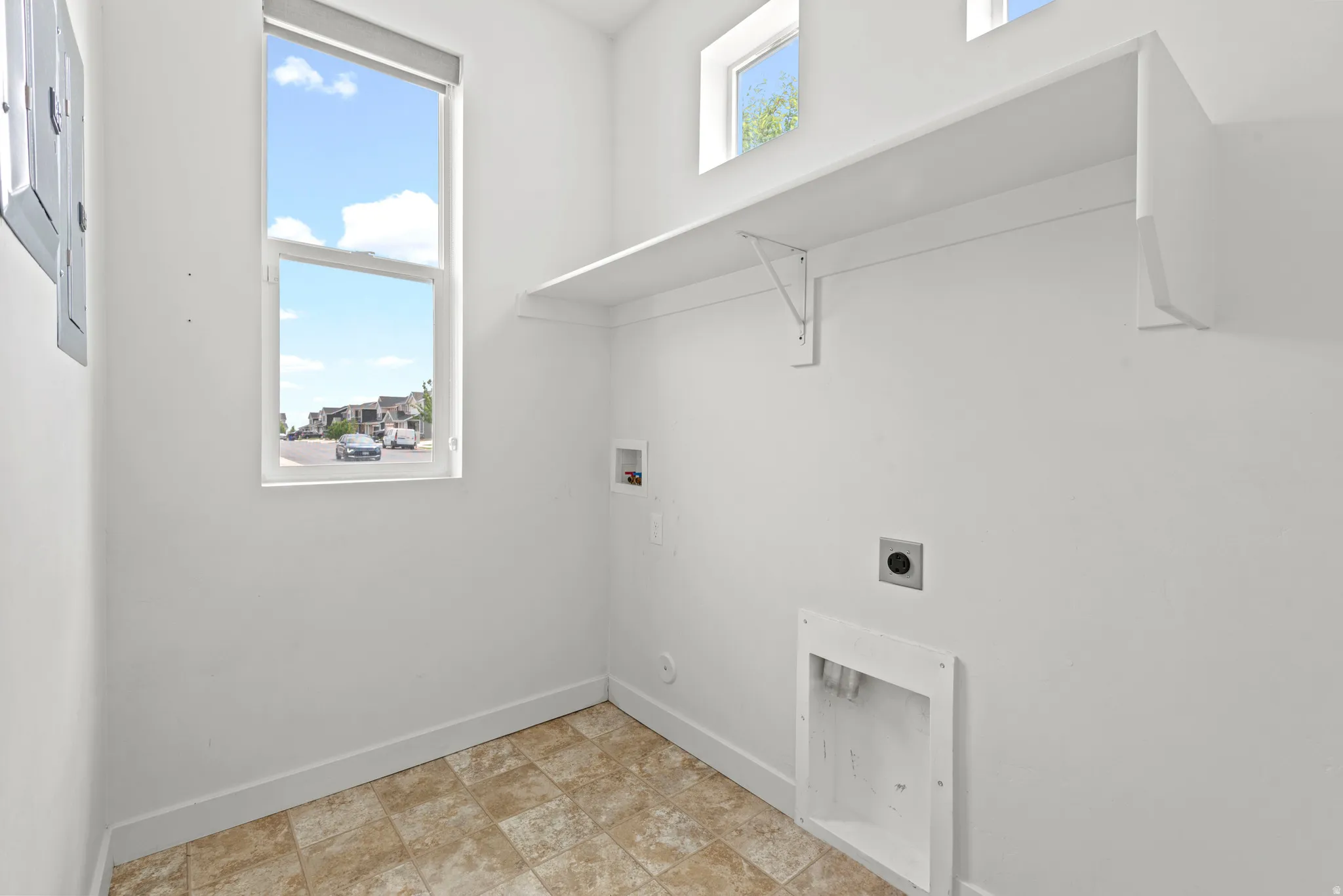 Utility room featuring a tall window, two smaller upper windows, a built-in shelf, and tile flooring