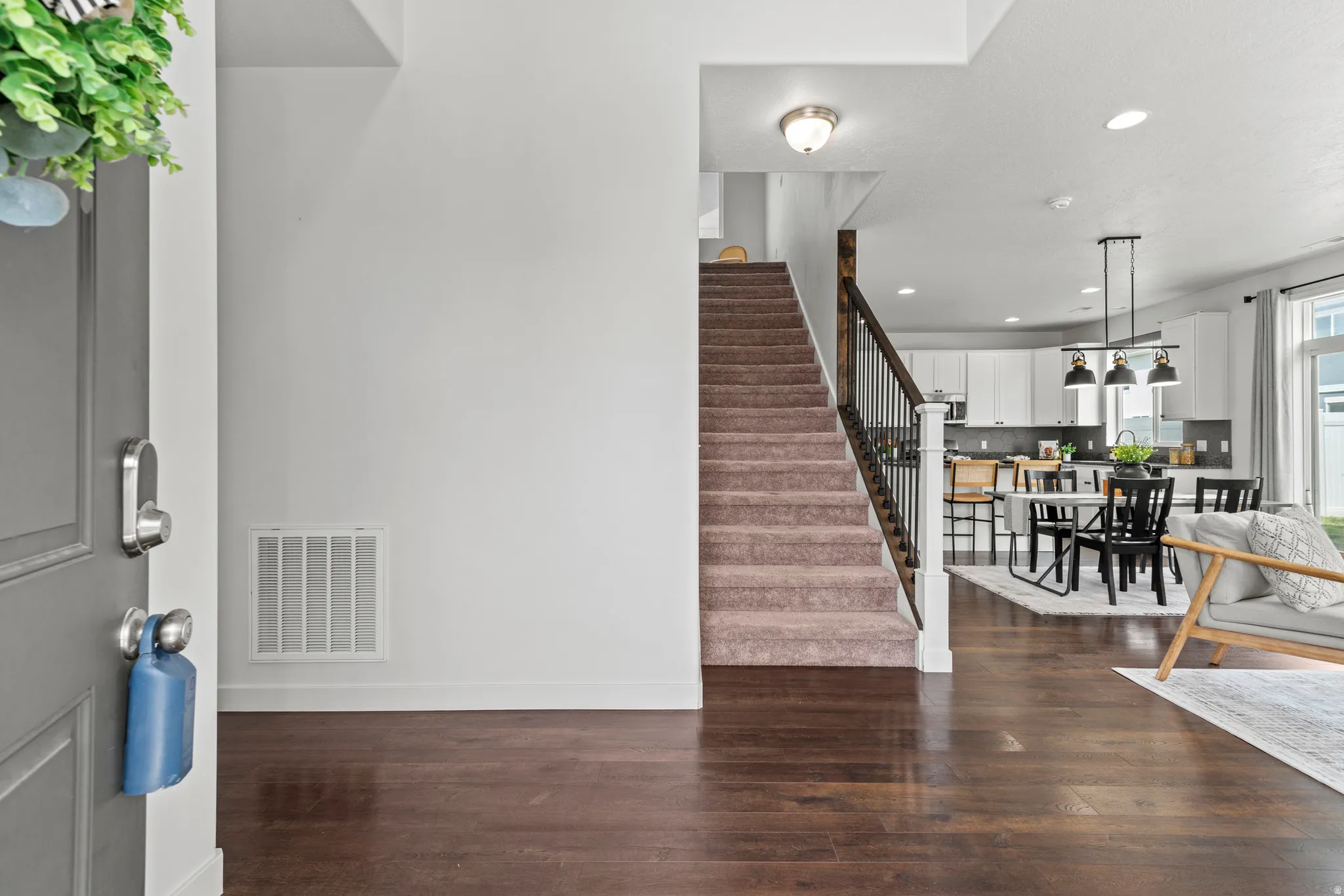Rich wood-finish flooring provides a striking contrast to the white walls, creating an inviting entry