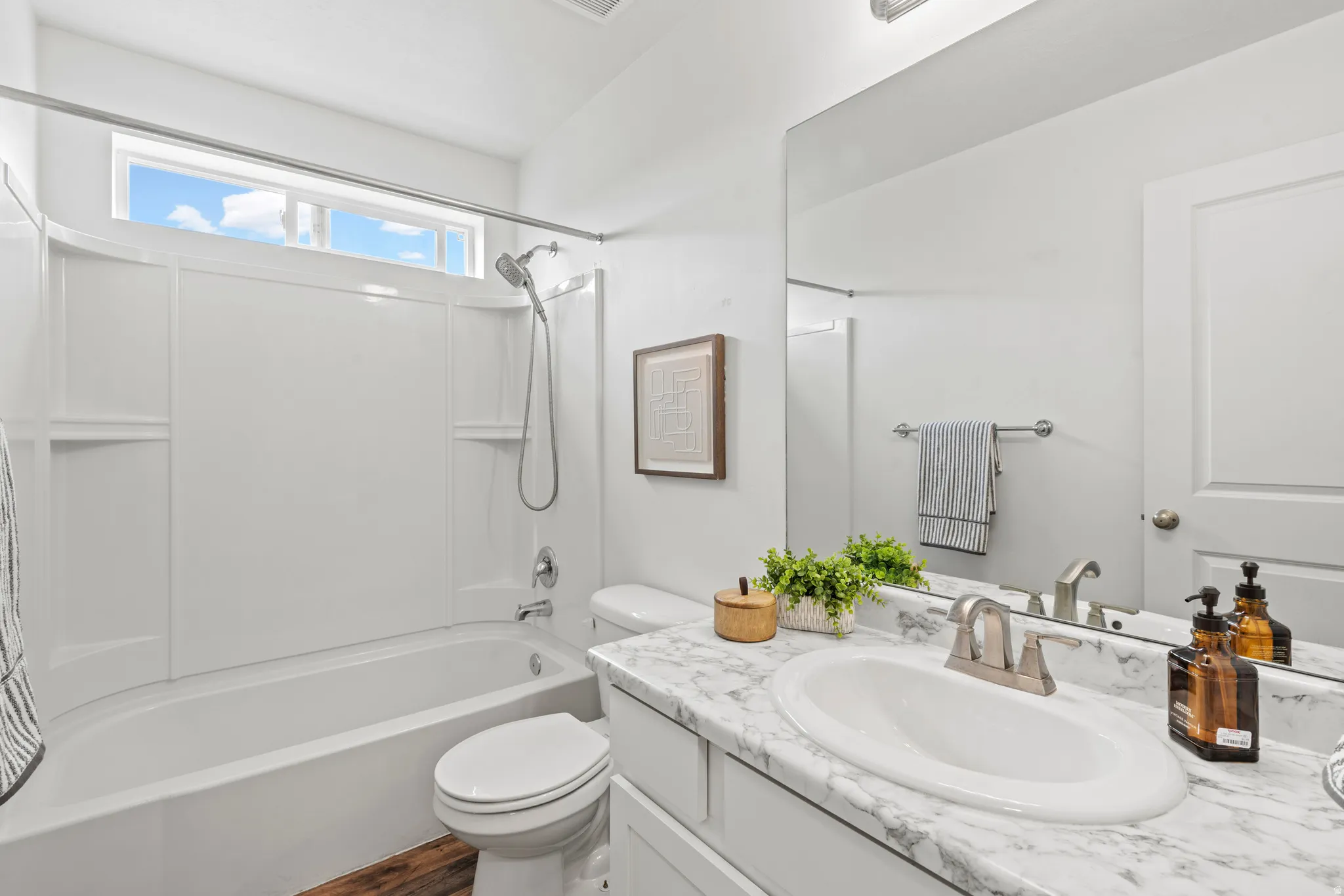 Bathroom featuring a full-size bathtub with integrated shower, single-handle faucet, and built-in shelving