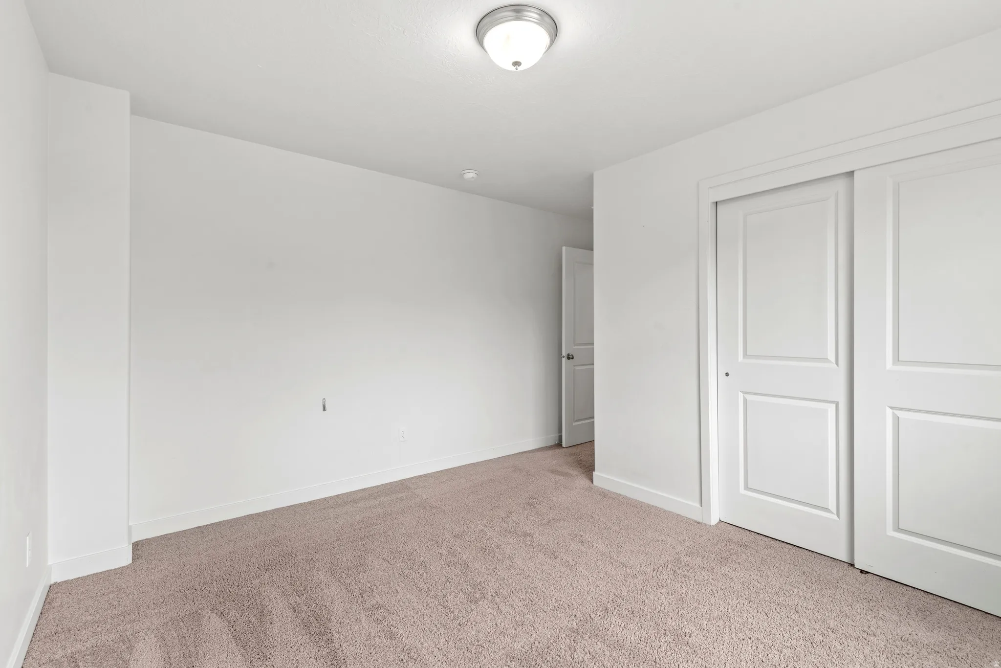Carpeted room featuring white walls, white trim, and a flush-mount ceiling light fixture